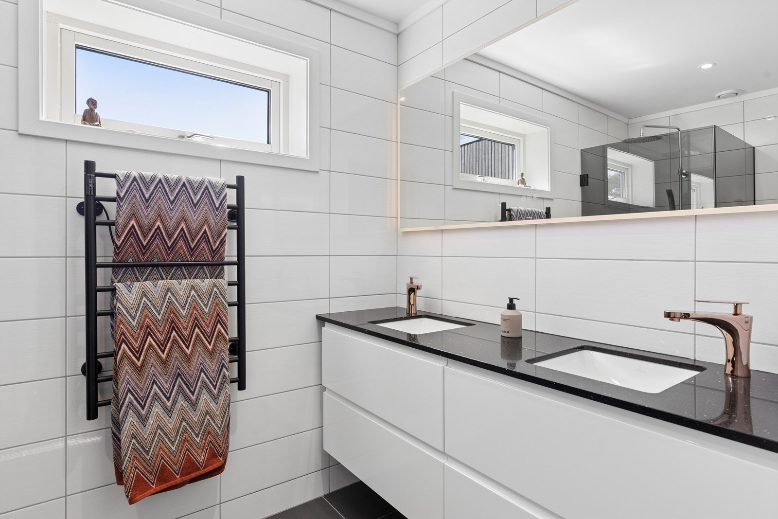 Badet er praktisk innredet med elektrisk håndkletørker og dobbel servant. Speilet har innebygget varme og belysning. Galleribilde