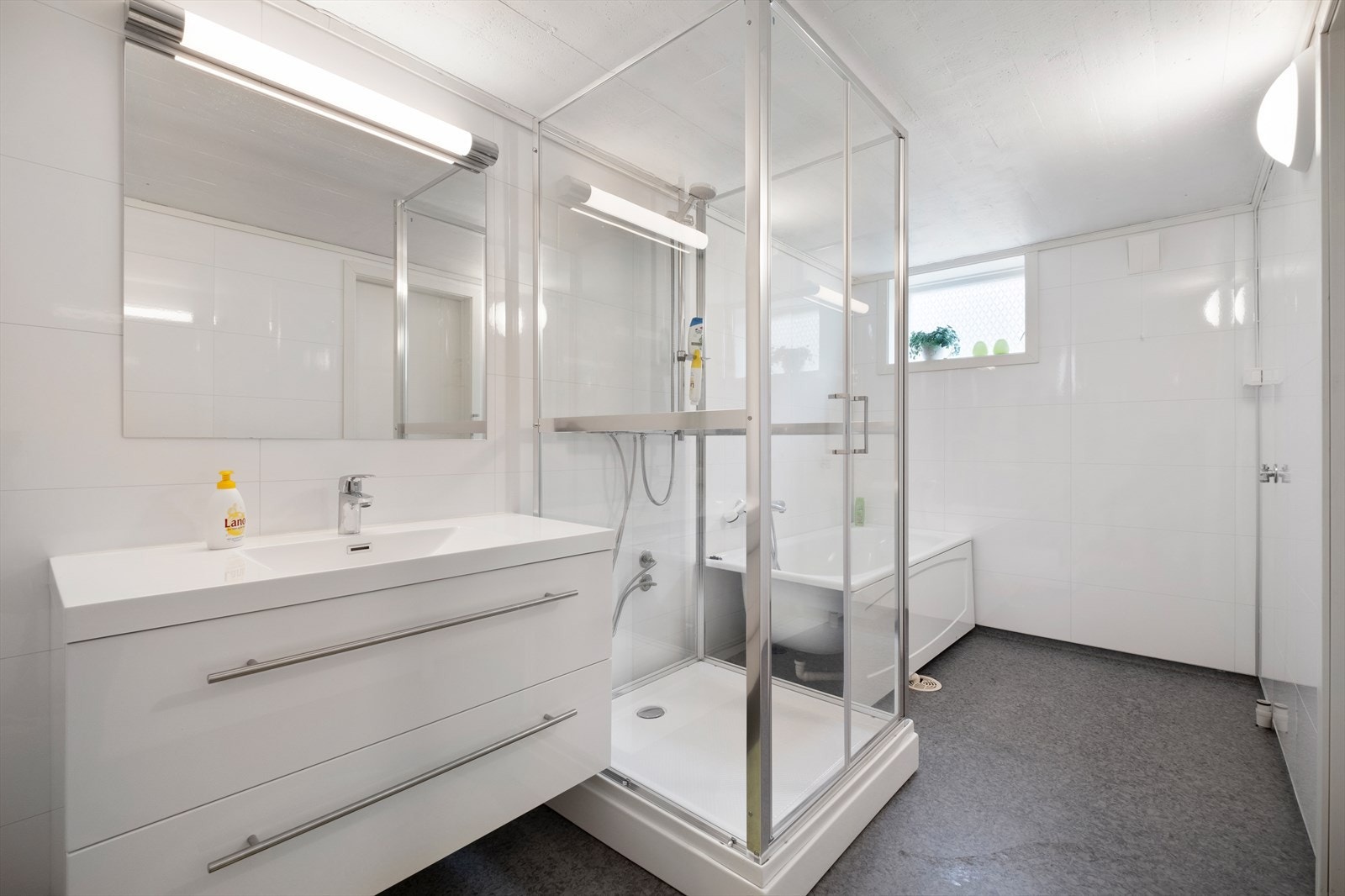 Badet har dusjkabinett og badekar, samt fliser på gulvet. Galleribilde