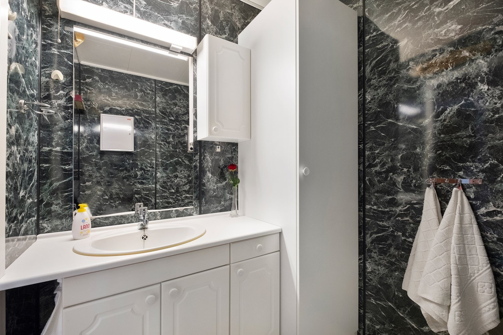 Badet har baderomsplater på veggene og servant med slette fronter. Galleribilde