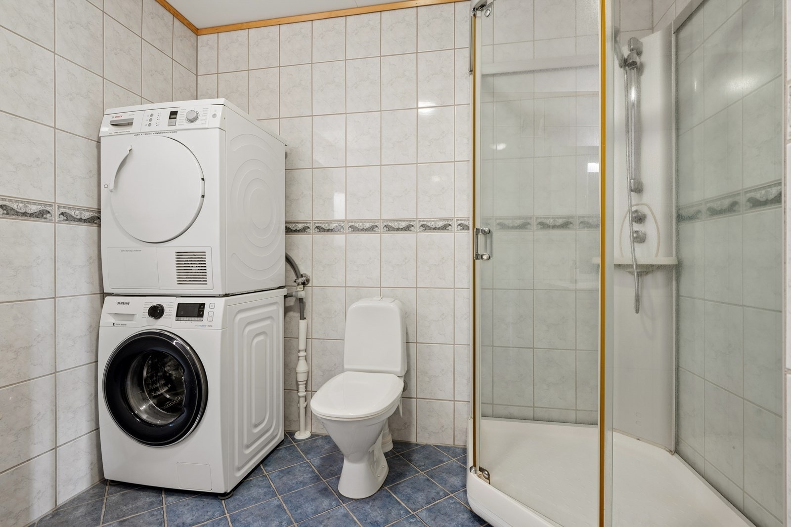 Badet er utstyrt med dusjkabinett, gulvstående toalett og opplegg for vaskemaskin. Galleribilde