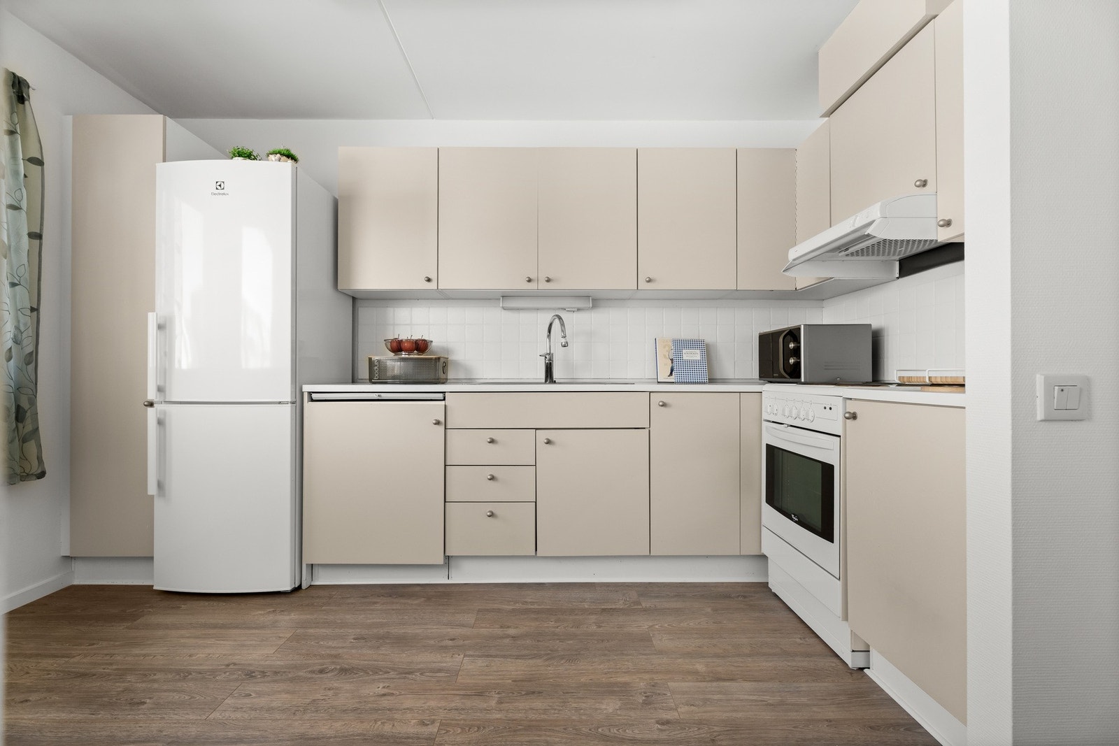 Innredningen har lyse, glatte fronter og hvit laminatbenkeplate med nedfelt kum i stål. Galleribilde
