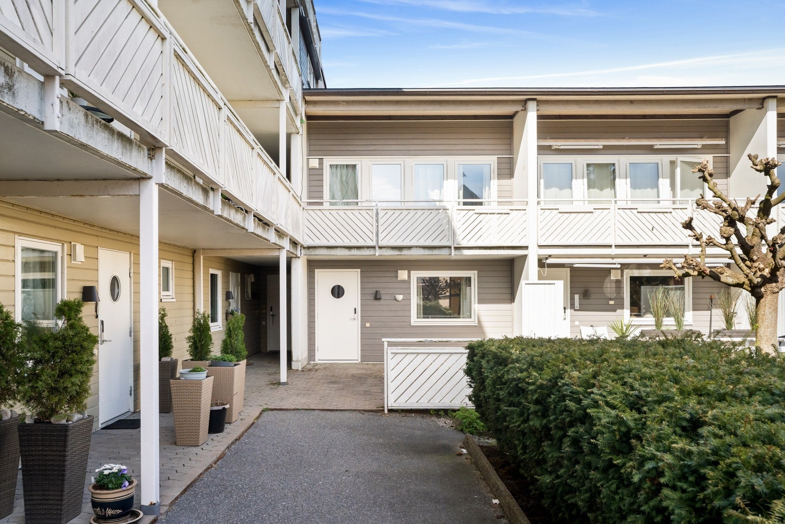 Leiligheten har et pent, overbygd inngangsparti med en stor, steinbelagt velkomstterrasse og veggmontert utebelysning. Galleribilde
