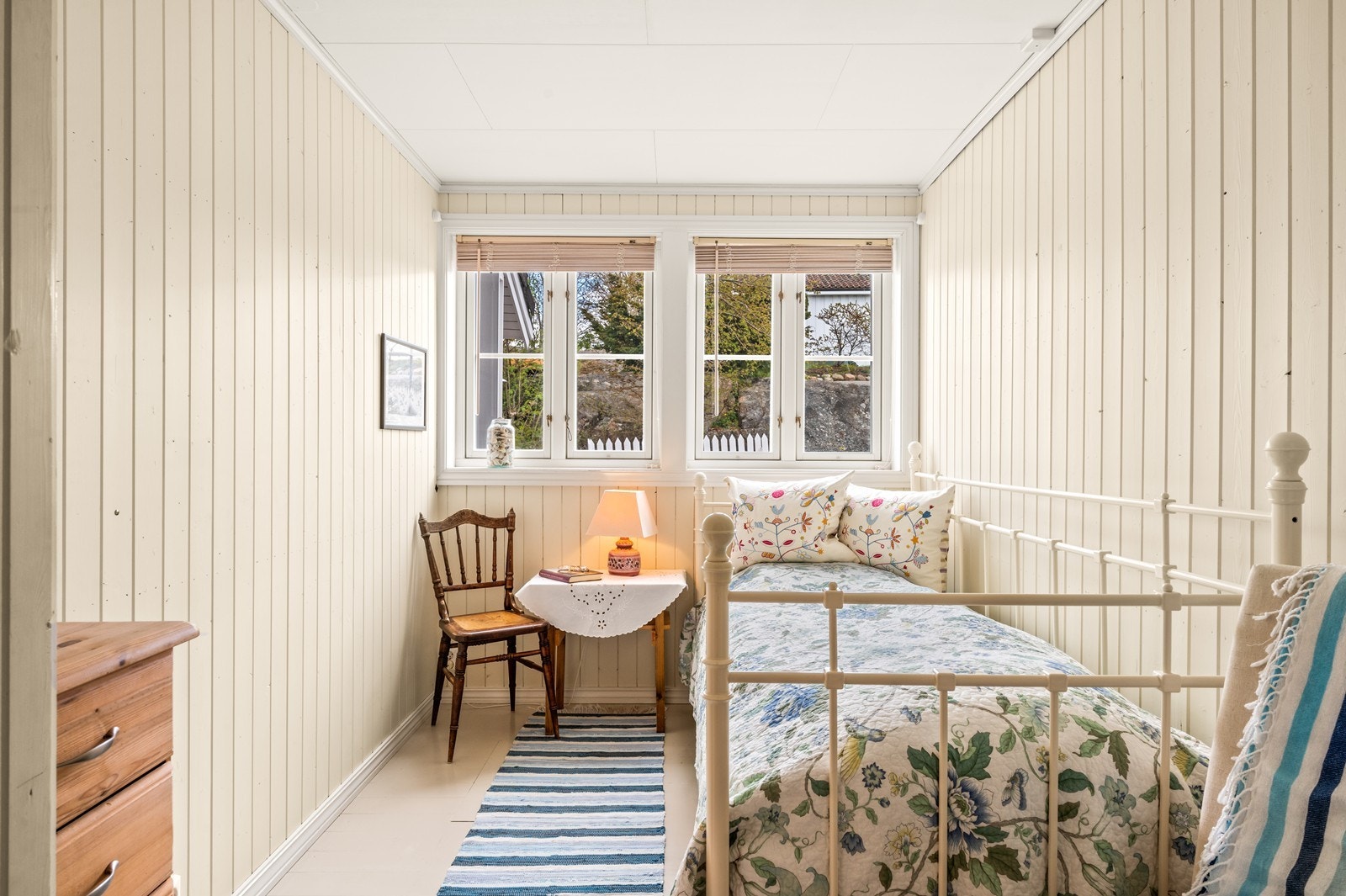 Soverom med trepanel på veggene og vindu mot gårdsplass. Galleribilde