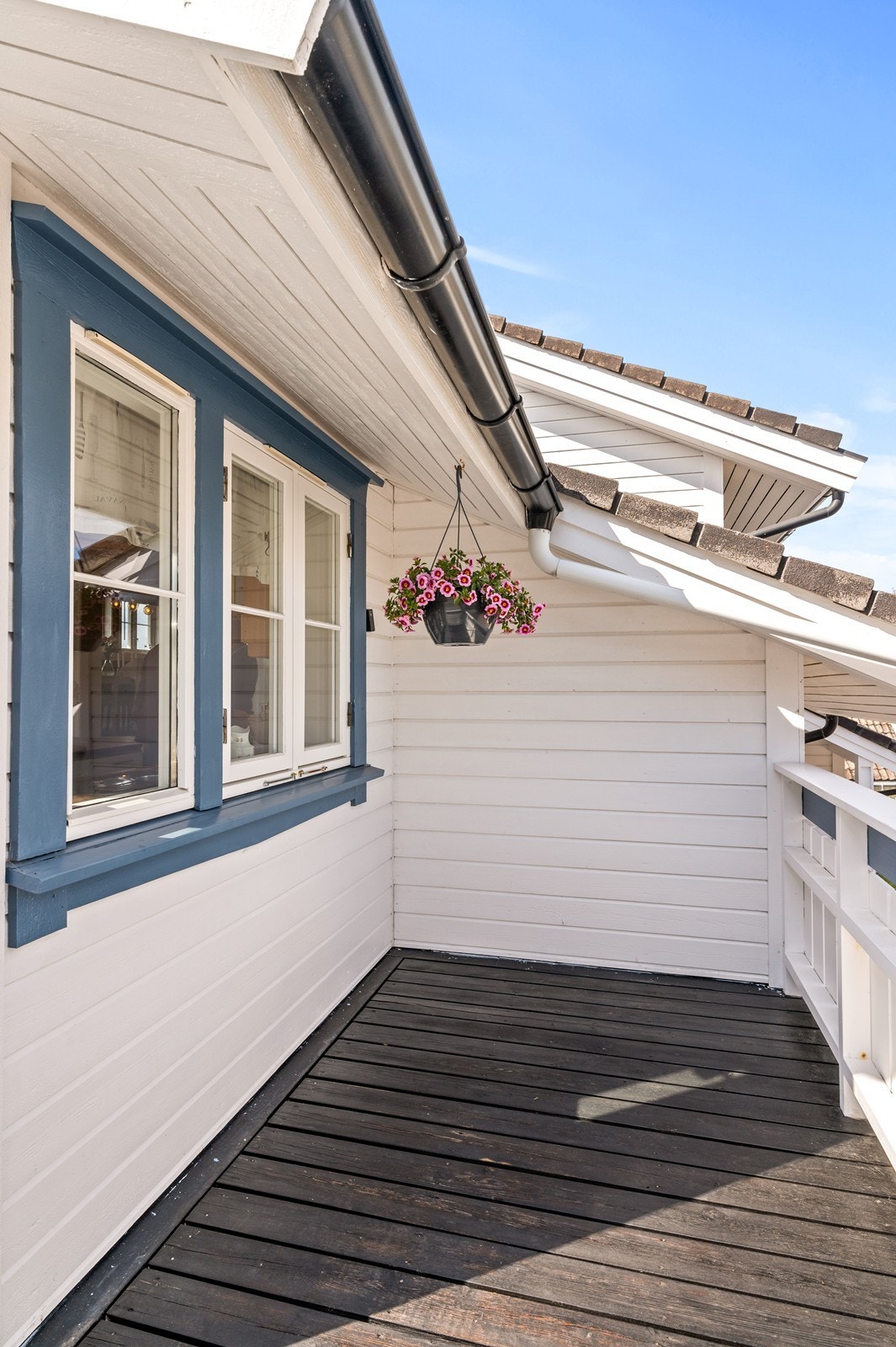 Detalj fra fasaden med liggende bordkledning og tak tekket med betongtakstein. Galleribilde