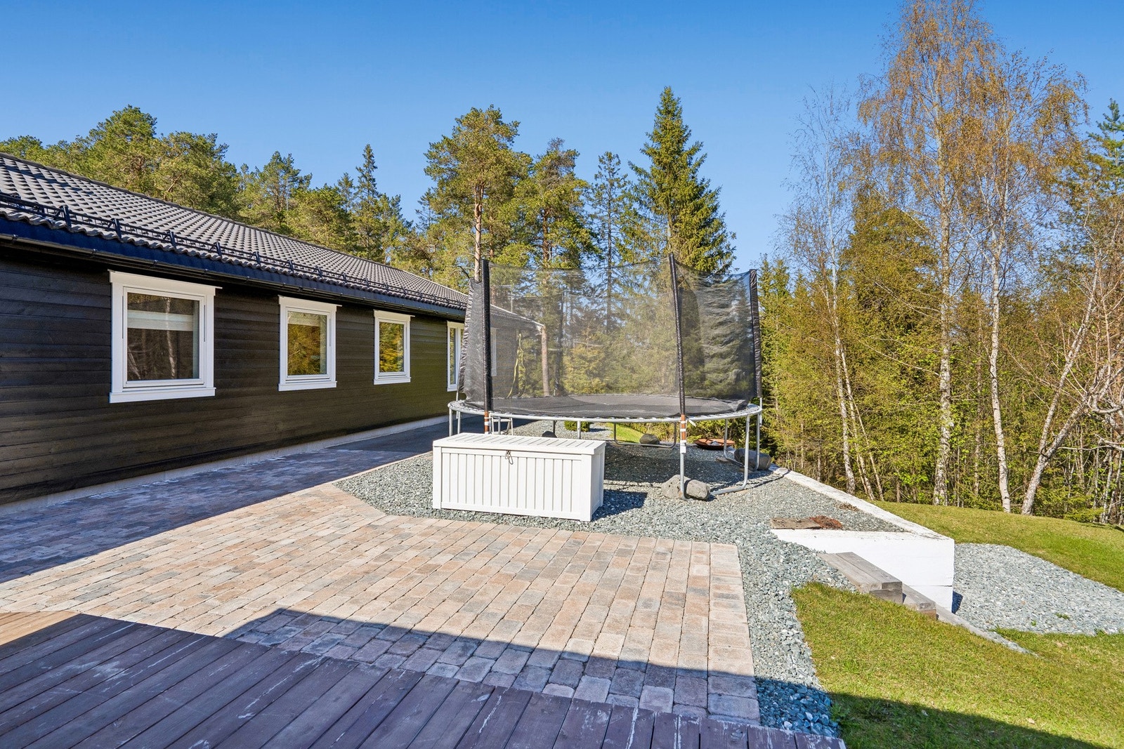 Steinlagt uteområde med god boltreplass. Her har man plass til trampoline og lekestativ om man skulle ønske. Galleribilde
