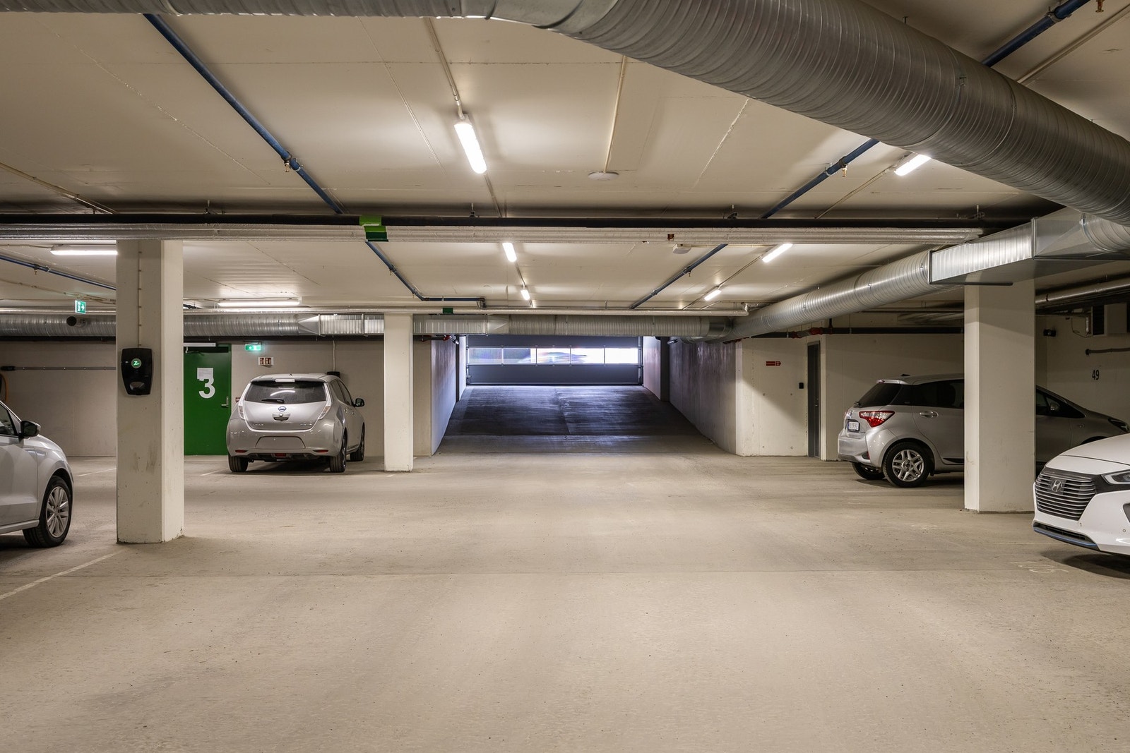 Parkeringsplass med lader for elbil i oppvarmet p-kjeller Galleribilde