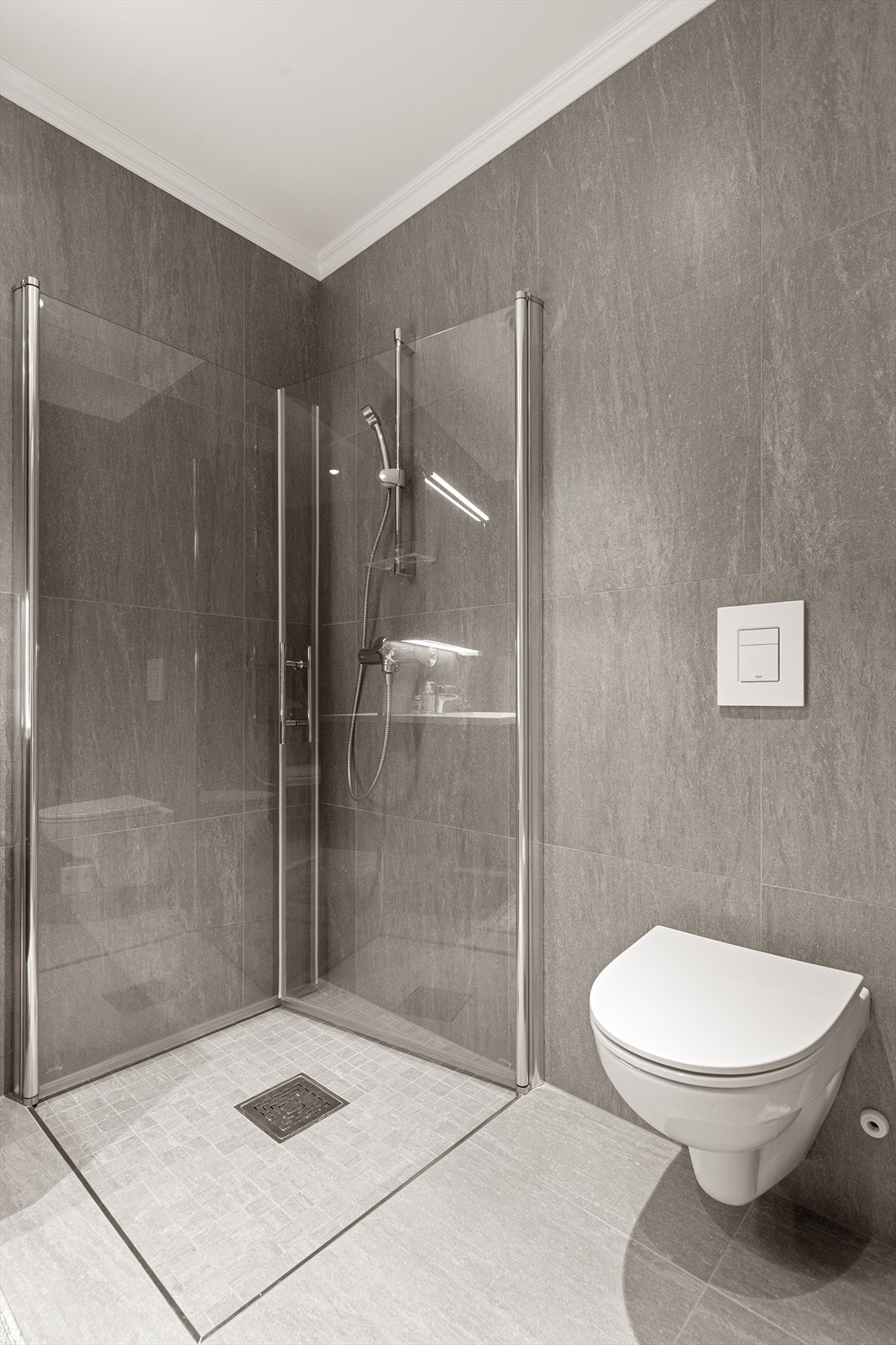 Badet er utstyrt med heldekkende servant med underskap, speilskap, dusjnisje og toalett Galleribilde