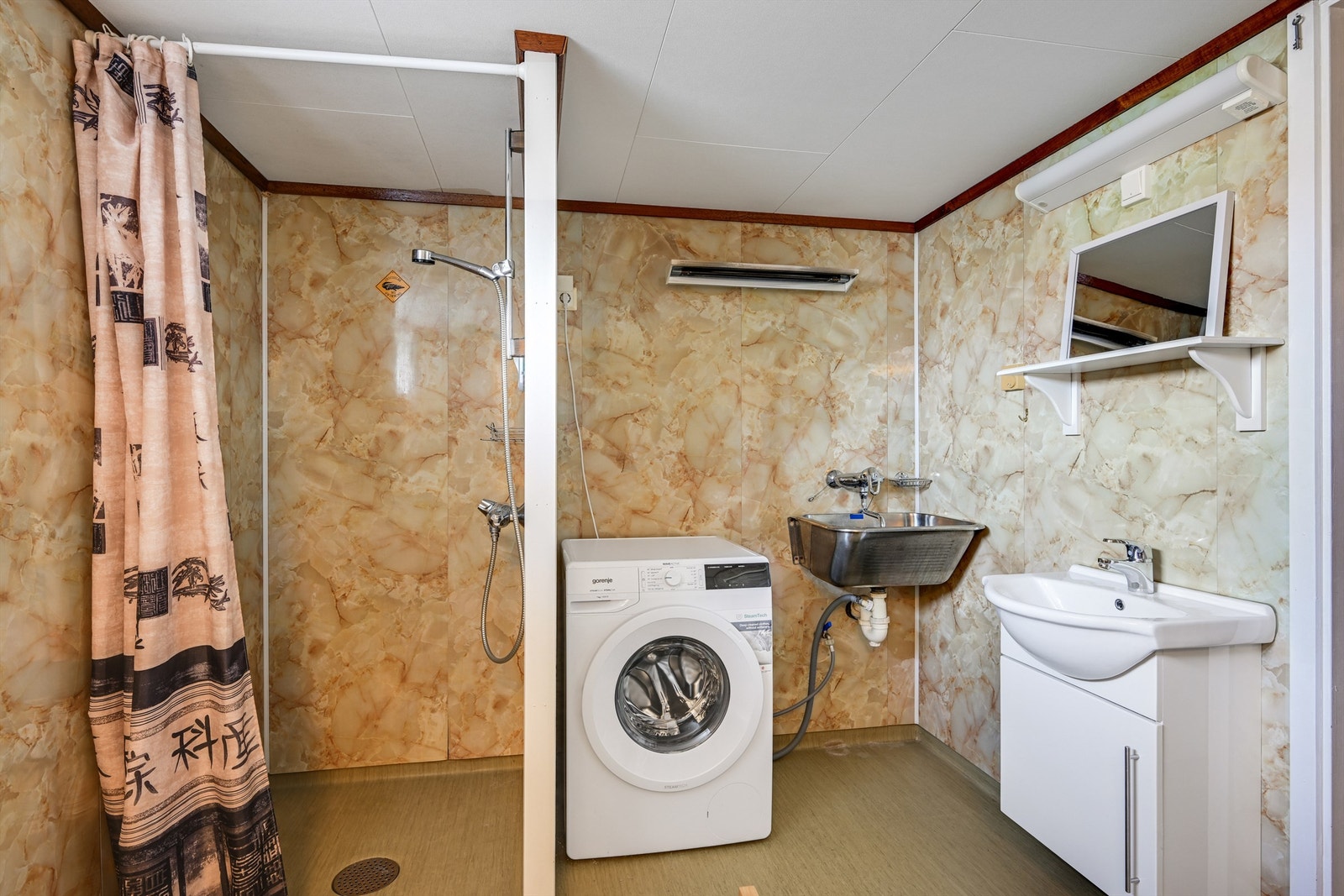 Badet i kjelleren har dusjnisje, skyllekum i stål og opplegg for vaskemaskin. Galleribilde