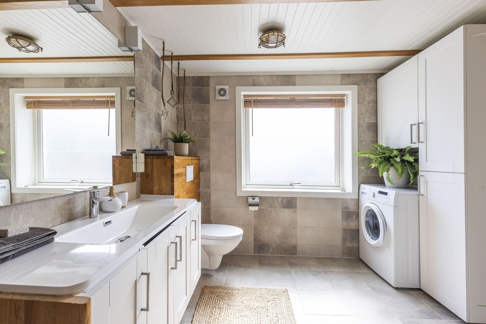 Badet har vegg hengt servant, godt med skapplass, og opplegg for vaskemaskin. Galleribilde