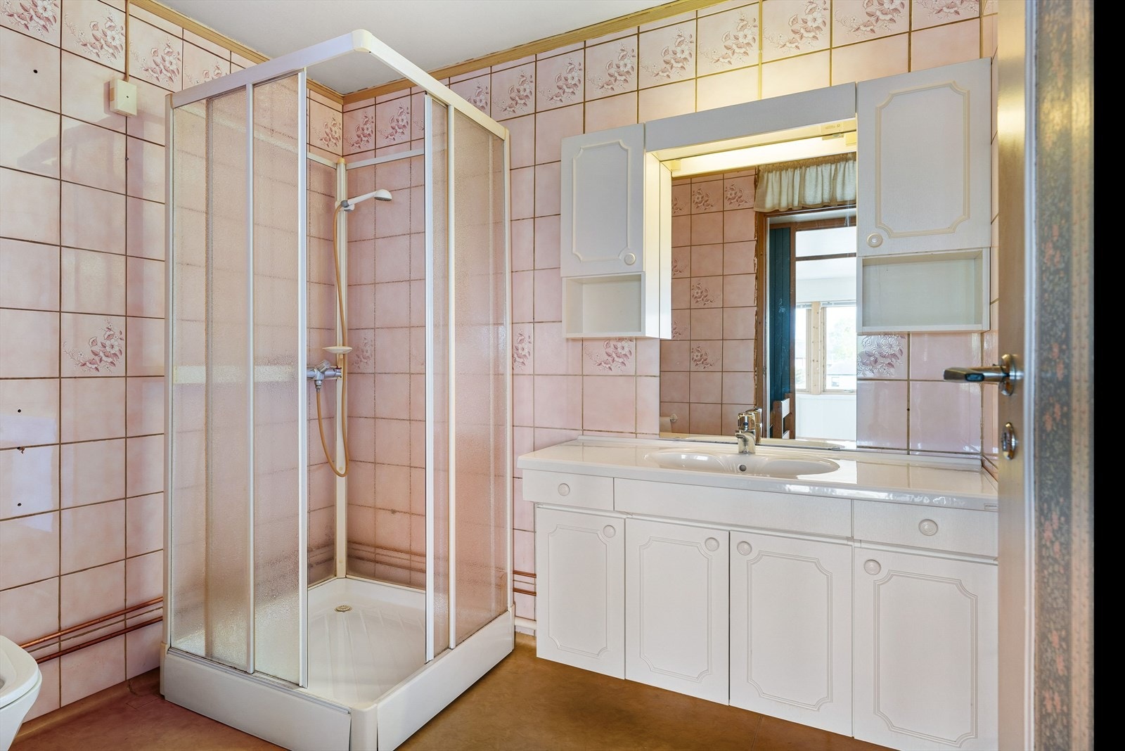 Badet måler 5 kvm og er utført med belegg på gulv og flis på vegger. Øvrig innredning består av toalett, dusjkabinett og et romslig baderomsmøbel med god lagringsplass. Galleribilde