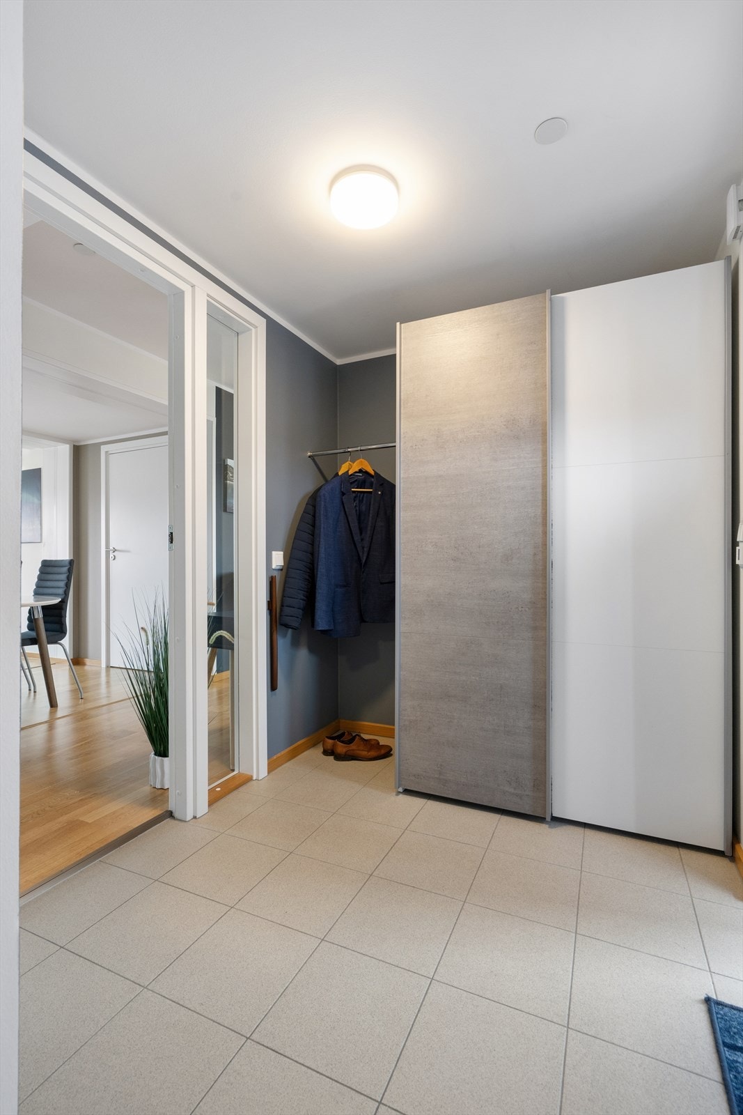 Man ønskes velkommen inn i en romslig entré som er praktisk innredet med flislagt gulv og en romslig skyvedørsgarderobe som gir god lagringsplass til yttertøy og sko. Galleribilde