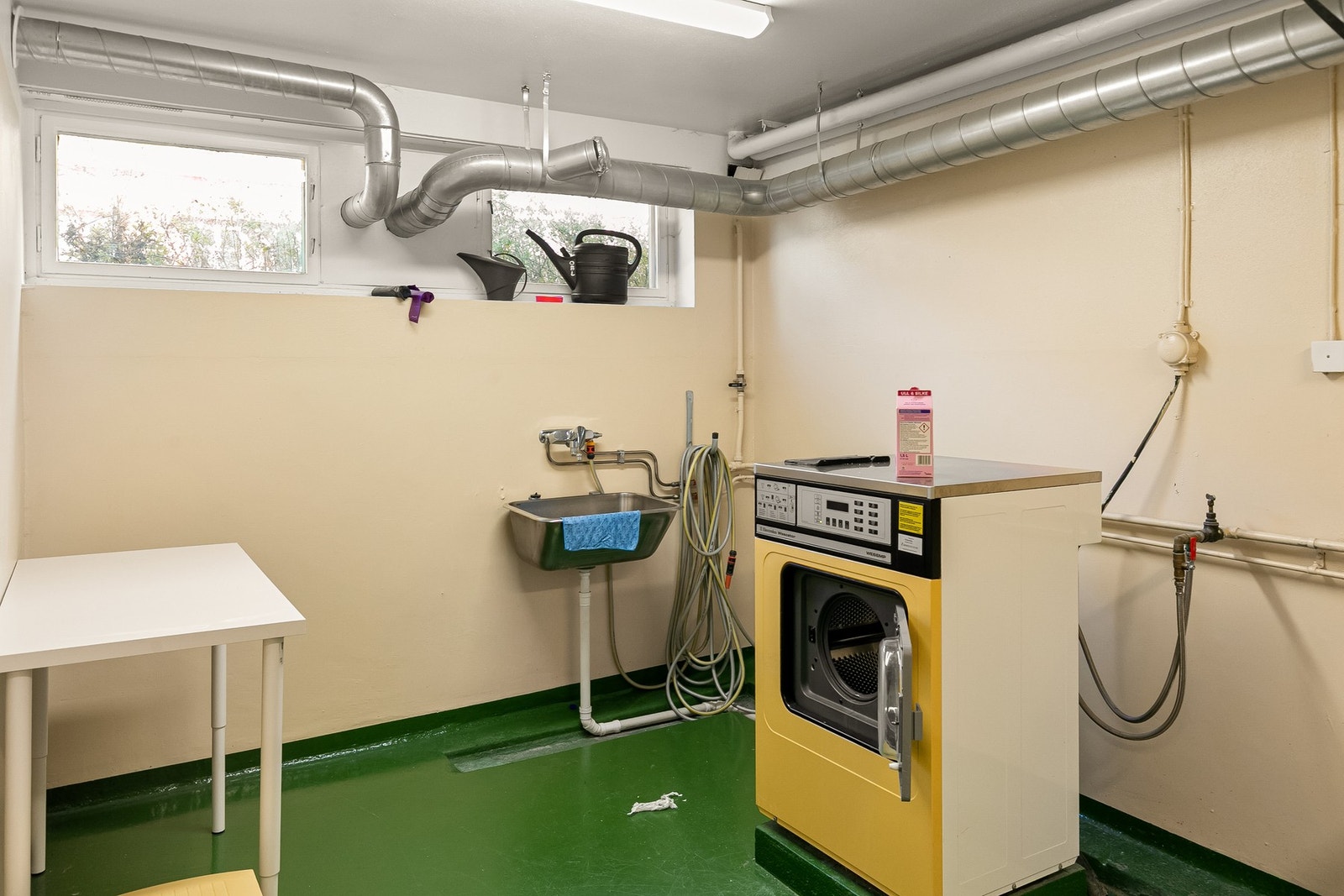 Fellesvaskeri med to vaskemaskiner, en tørketrommel og et tørkeskap tilgjengelig. Galleribilde