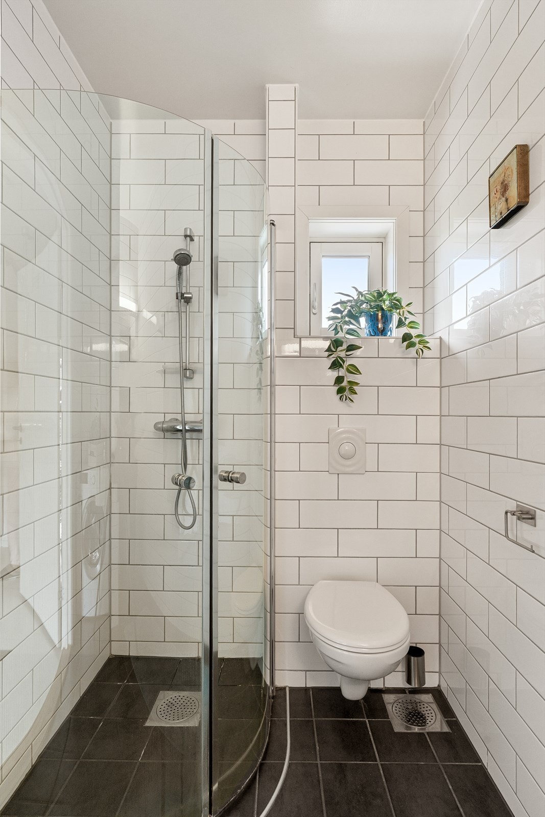 Badet er utstyrt med vegghengt toalett og dusjhjørne med innfellbare dører. Galleribilde