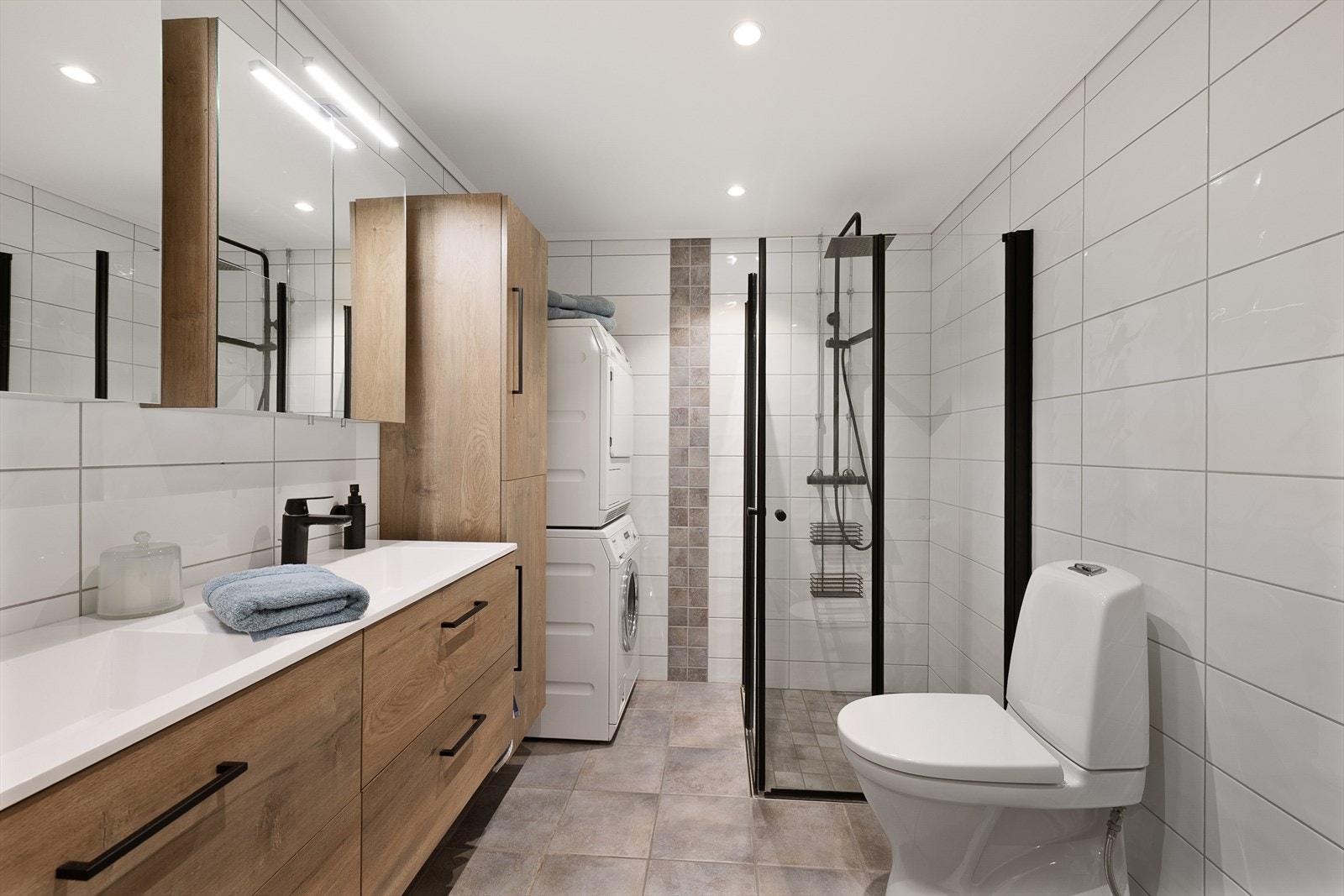 Badet har en moderne utførelse med mørke gulvfliser og hvite veggfliser. Galleribilde