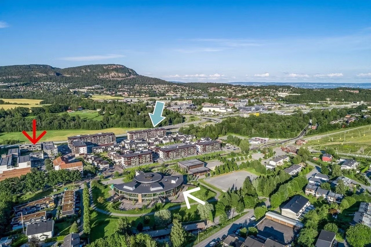 Sentral beliggenhet på nyere boligfelt Vøyenenga - blokken/leiligheten ligger litt til venstre for blå pil, butikksenter (rød pil), Vøyenenga ungdomsskole (hvit pil) Galleribilde