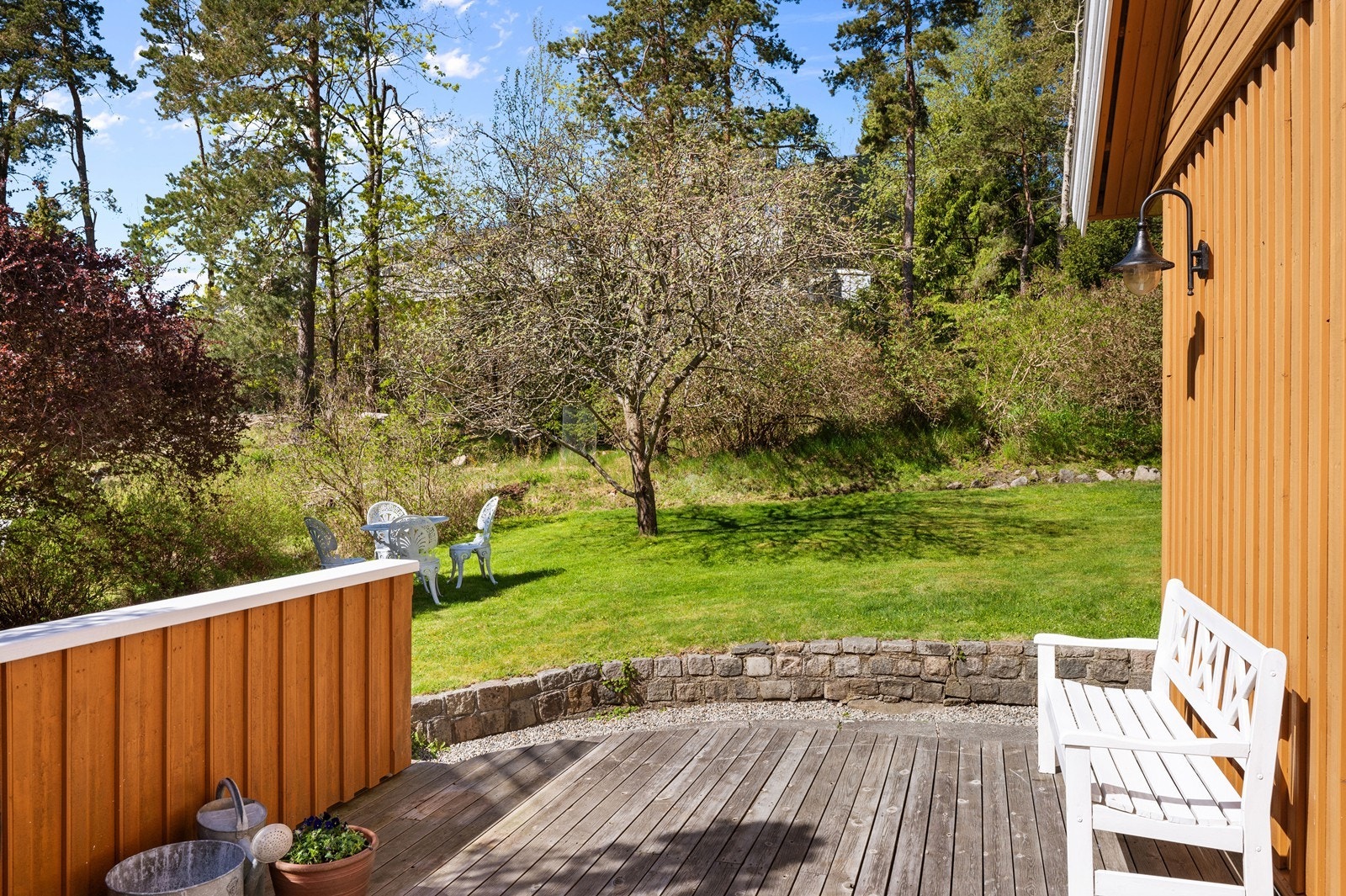 Fra terrassen i første etasje er det direkte tilgang til en stor, skrånende hage med gressplen og beplantning. Om sommeren sørger vegetasjonen for lite innsyn. Galleribilde