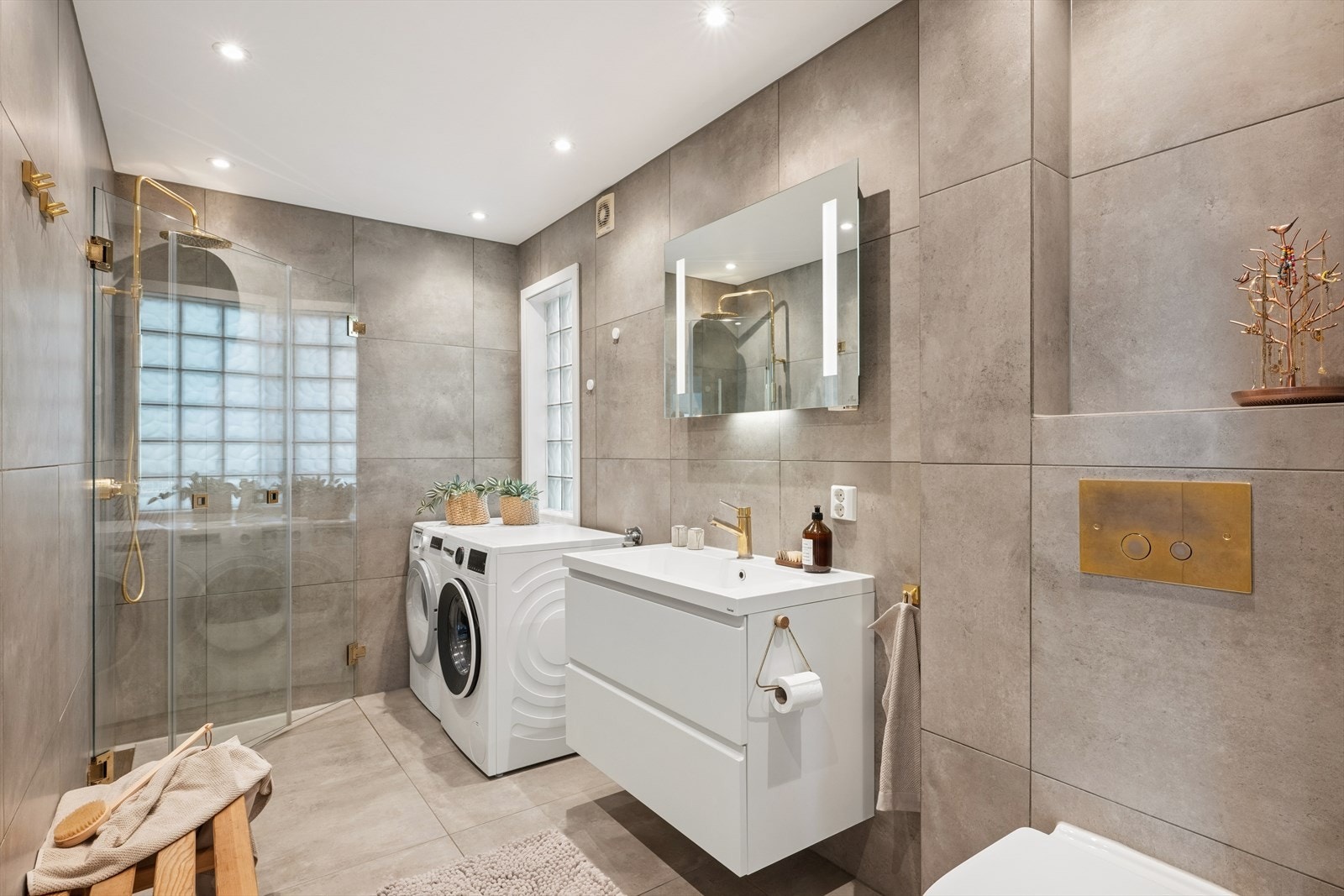 Lekkert baderom fra 2019. Badet fremstår som innbydende, delikat og funksjonelt med moderne materialvalg. Beige fliser kombinert med gull detaljer gir et tidsriktig og elegant uttrykk. Galleribilde