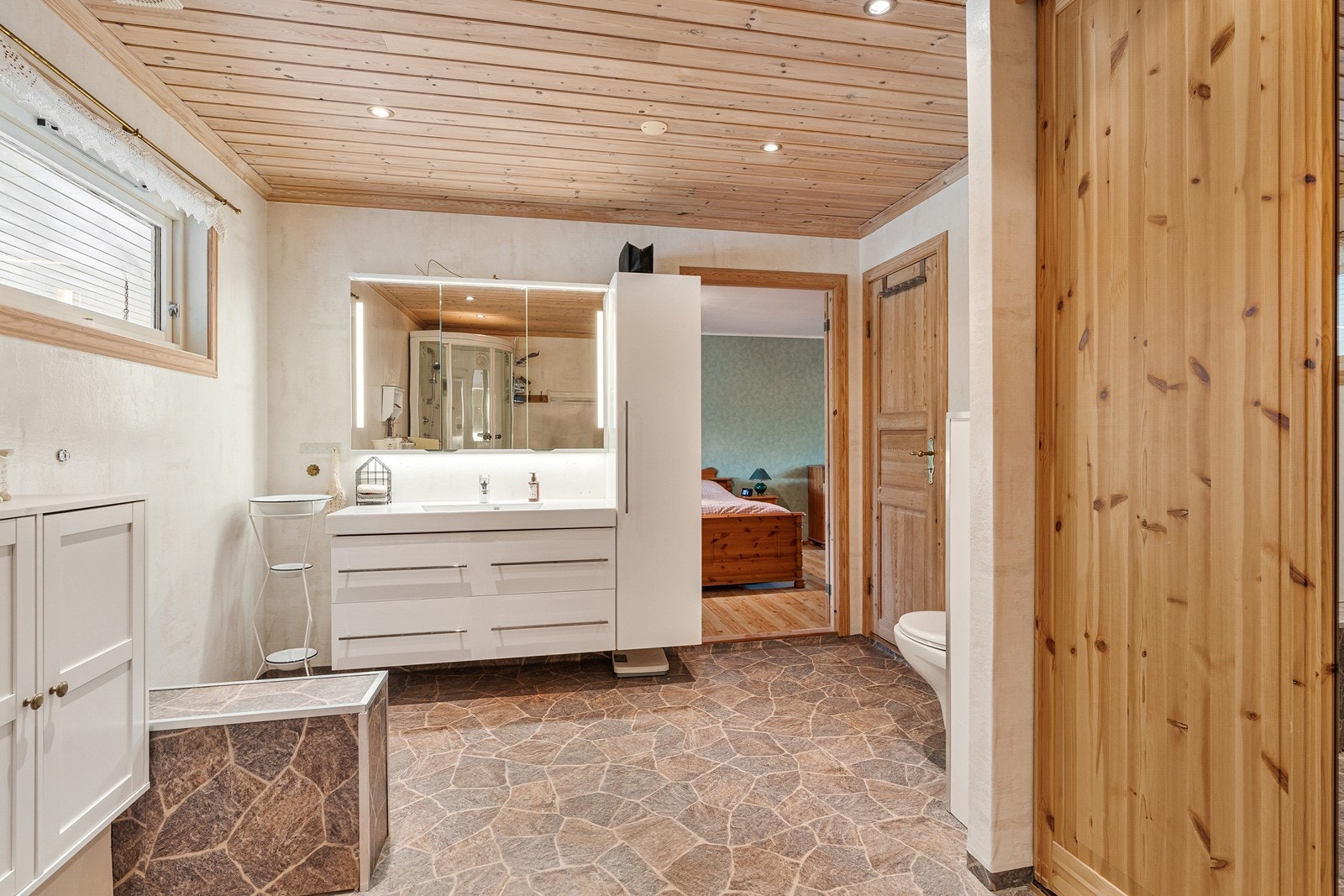Badet er praktisk og pent innredet med dusjkabinett, vegghengt toalett og baderomsinnredning. Badet har praktisk adkomst både fra hovedsoverommet og gangen Galleribilde