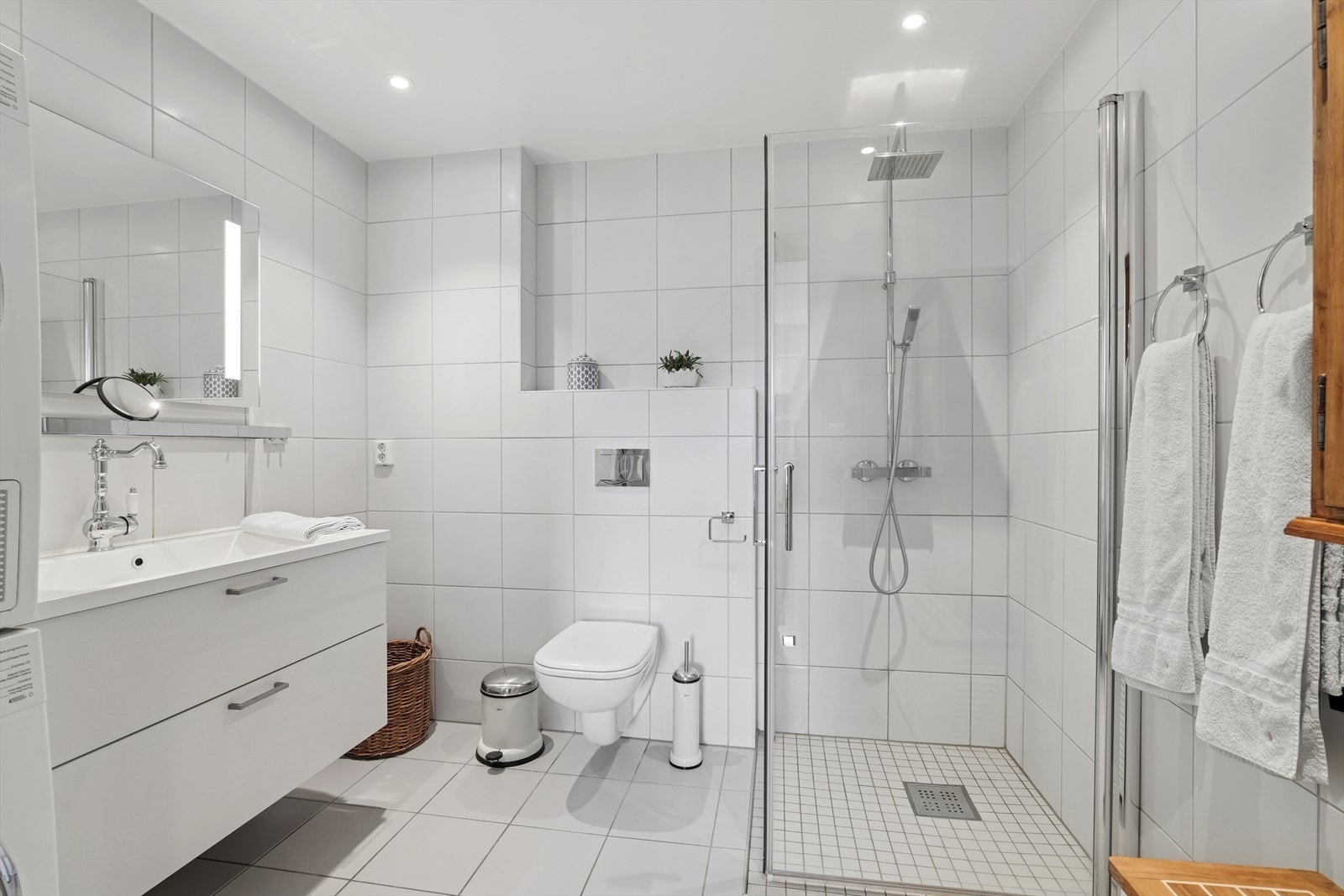 Badet er utstyrt med innredning med servant, speil med belysning, vegghengt wc, dusj med vegger og opplegg for vaskemaskin, noe som gjør det praktisk og brukervennlig. Galleribilde