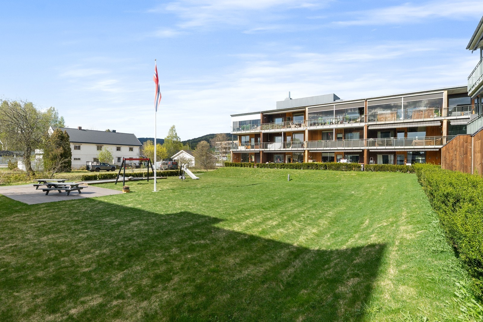 Sameiets felles tomt er pent opparbeidet med plenareal, beplantning, sittegrupper og lekeplass. Galleribilde
