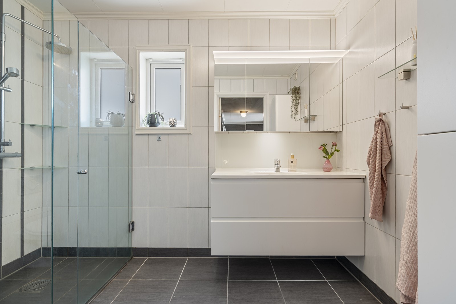 Badet er av god størrelse - Innredet med dusjnisje, veggmontert toalett, veggskap og baderomsmøbel med heldekkende servant. Galleribilde