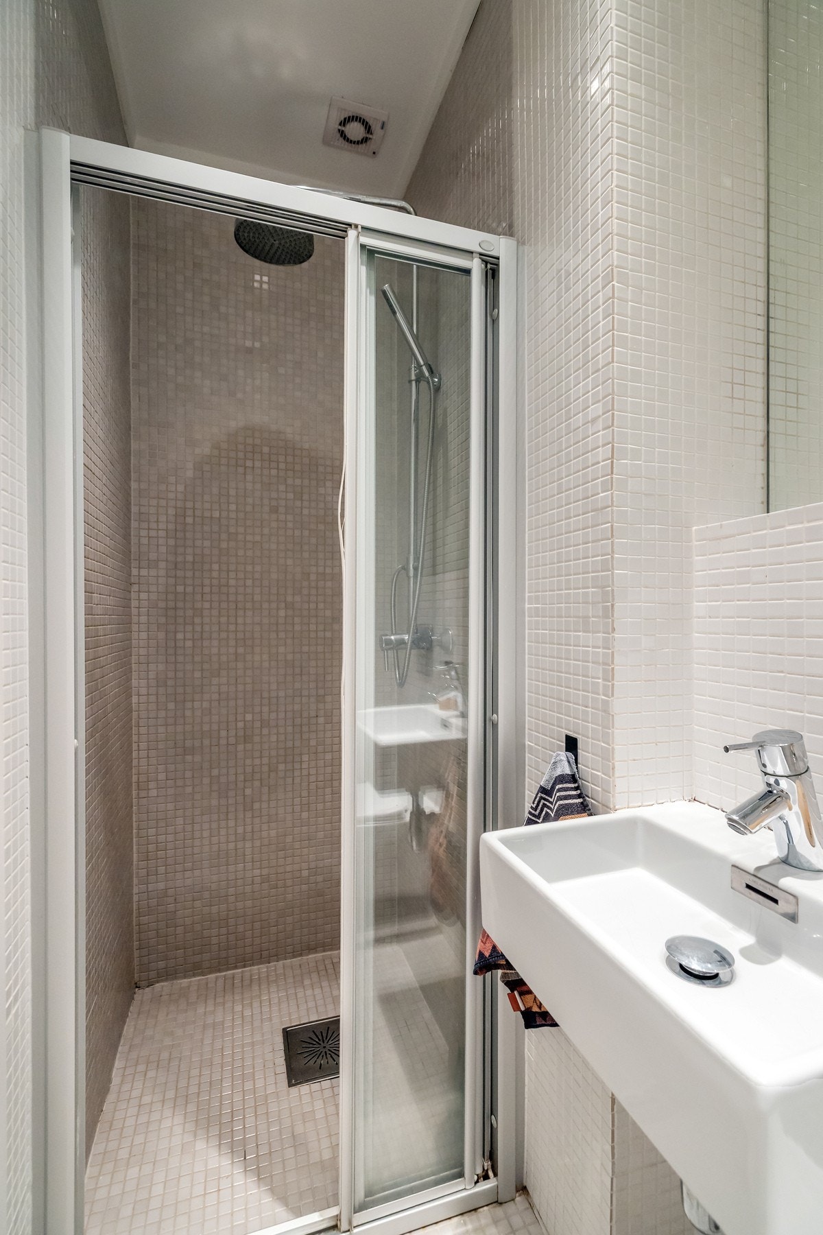 Badet er utstyrt med dusjnisje med glassdør, vegghengt servant og toalett Galleribilde