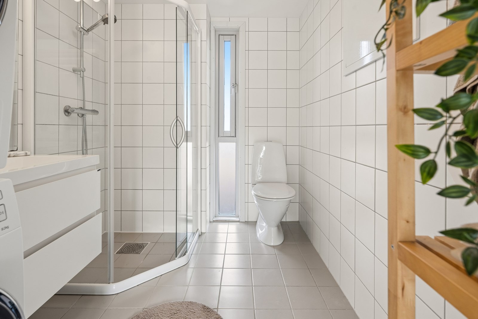 Badet er fra byggeår og er innredet med grå fliser på gulvet og hvite fliser på vegg. I gulvet har man også varmekabler for ekstra komfort. Galleribilde