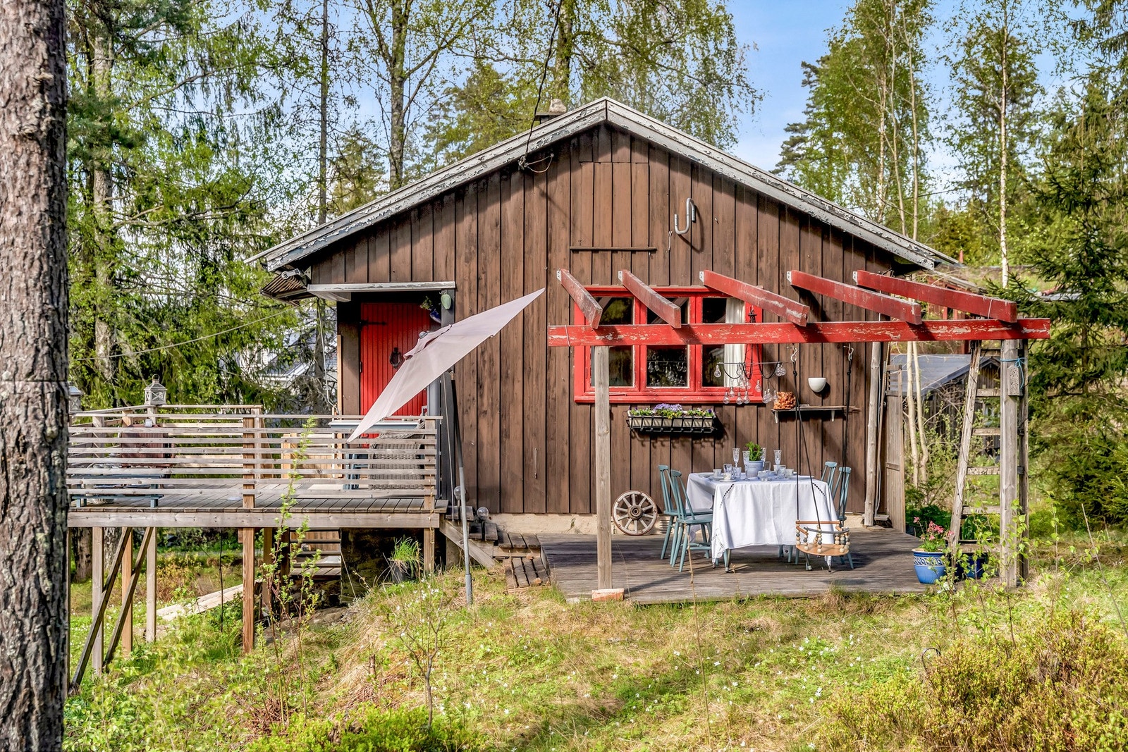 Koselig hytte med terrasse og pergola, omgitt av natur. Galleribilde