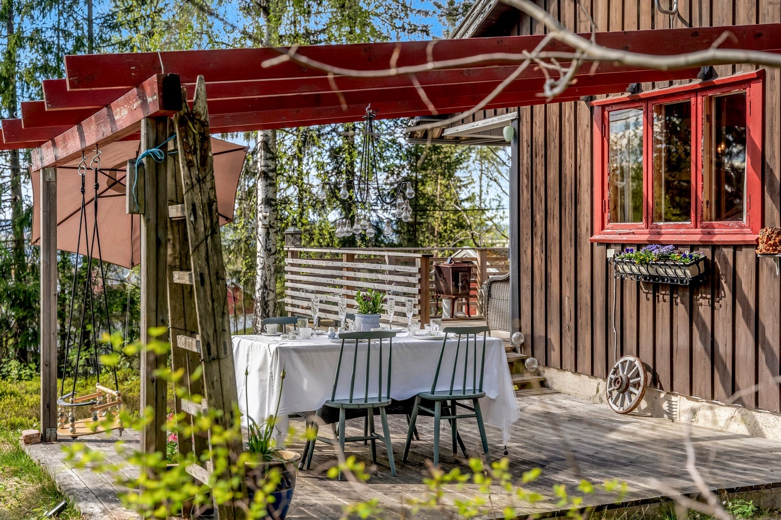 Koselig uteplass med pergola og spisebord, omgitt av trær og natur. Galleribilde