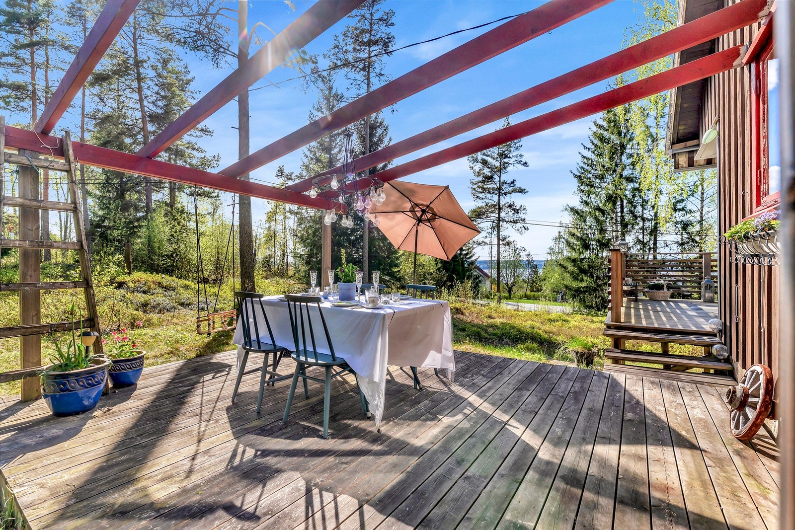 Terrasse med pergola, omgitt av skog og utsikt mot vannet. Galleribilde