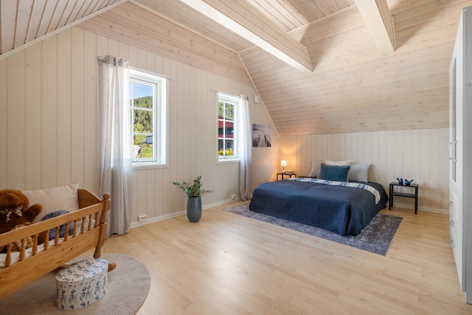 Romslig soverom på loftet med laminatgulv og panel i himlingen. Galleribilde