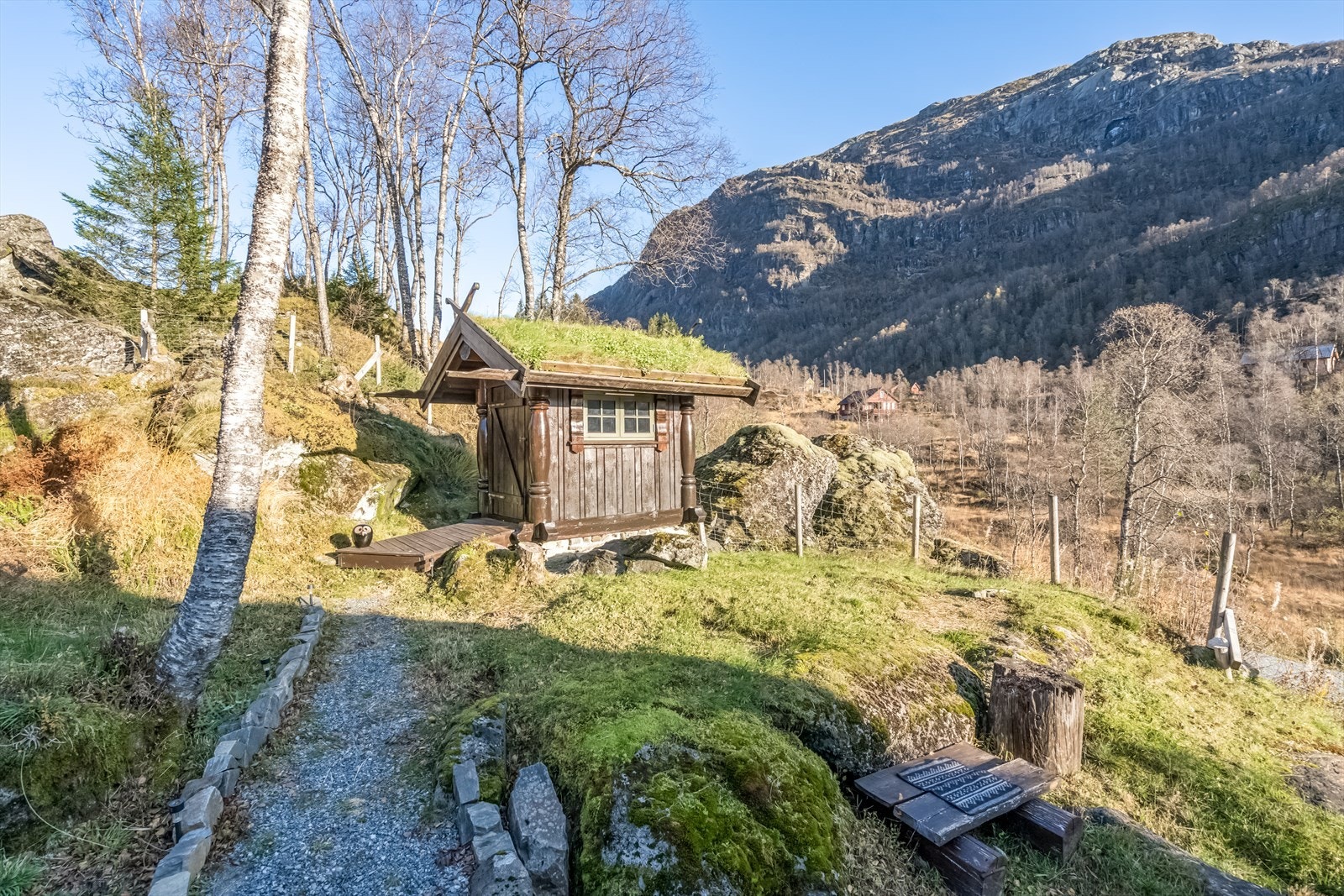Eiendommen inkluderer en frittstående bod med utedo, bygget i samme stil som hytta. Galleribilde