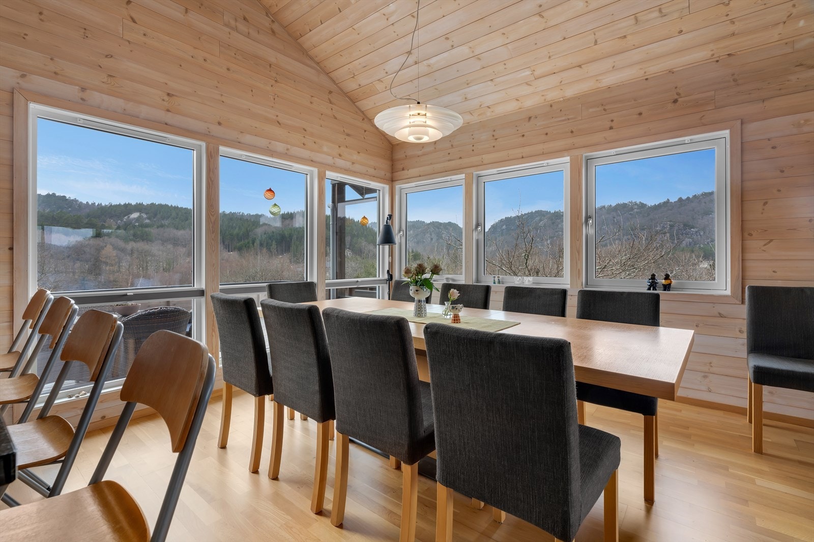 Spisestuen har plass til et stort langbord og er rammet inn av vinduer som slipper naturen inn. Galleribilde