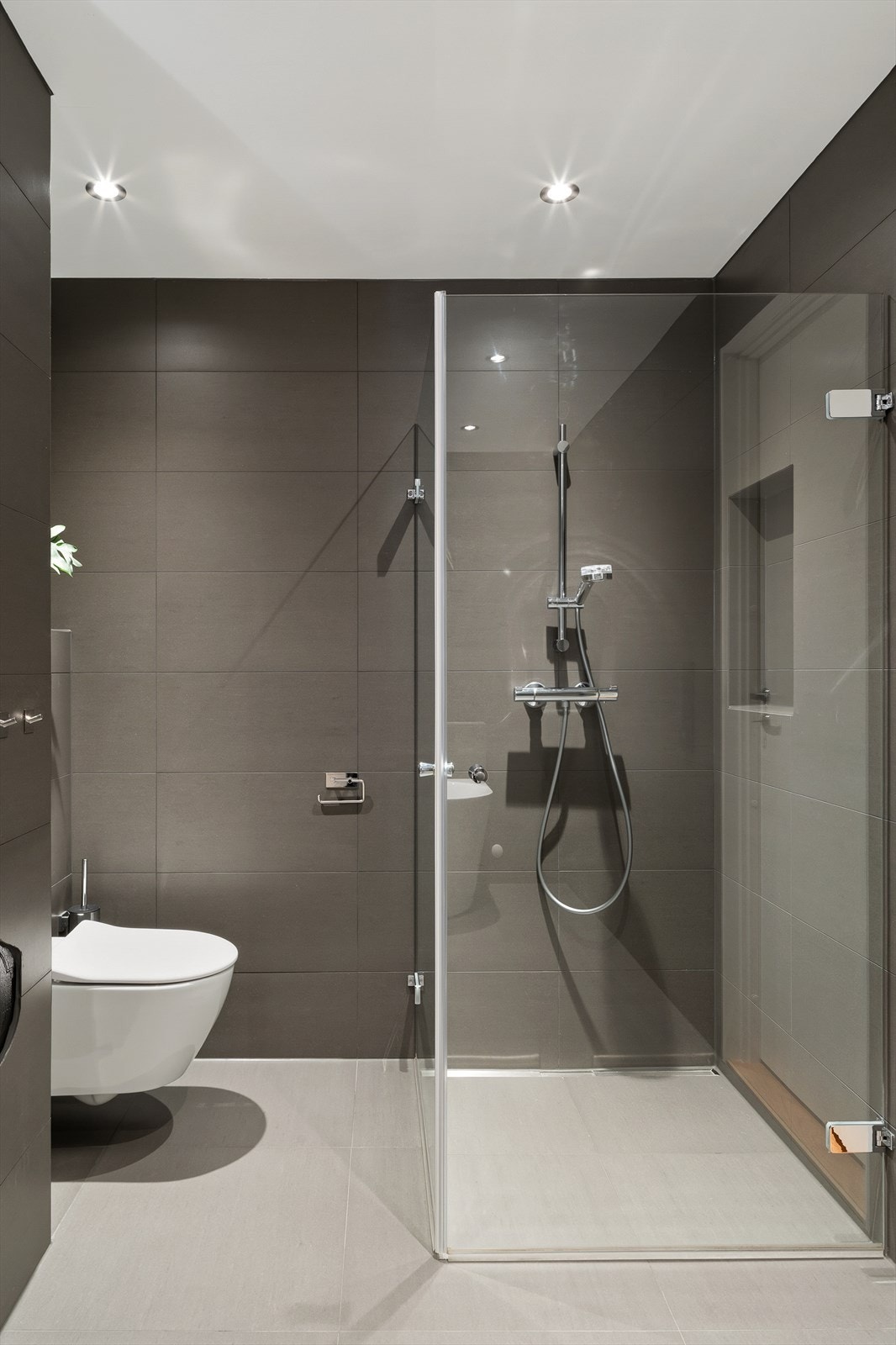 Badet er innredet med vask, speil med belysning, badekar, dusjhjørne og vegghengt toalett. Galleribilde