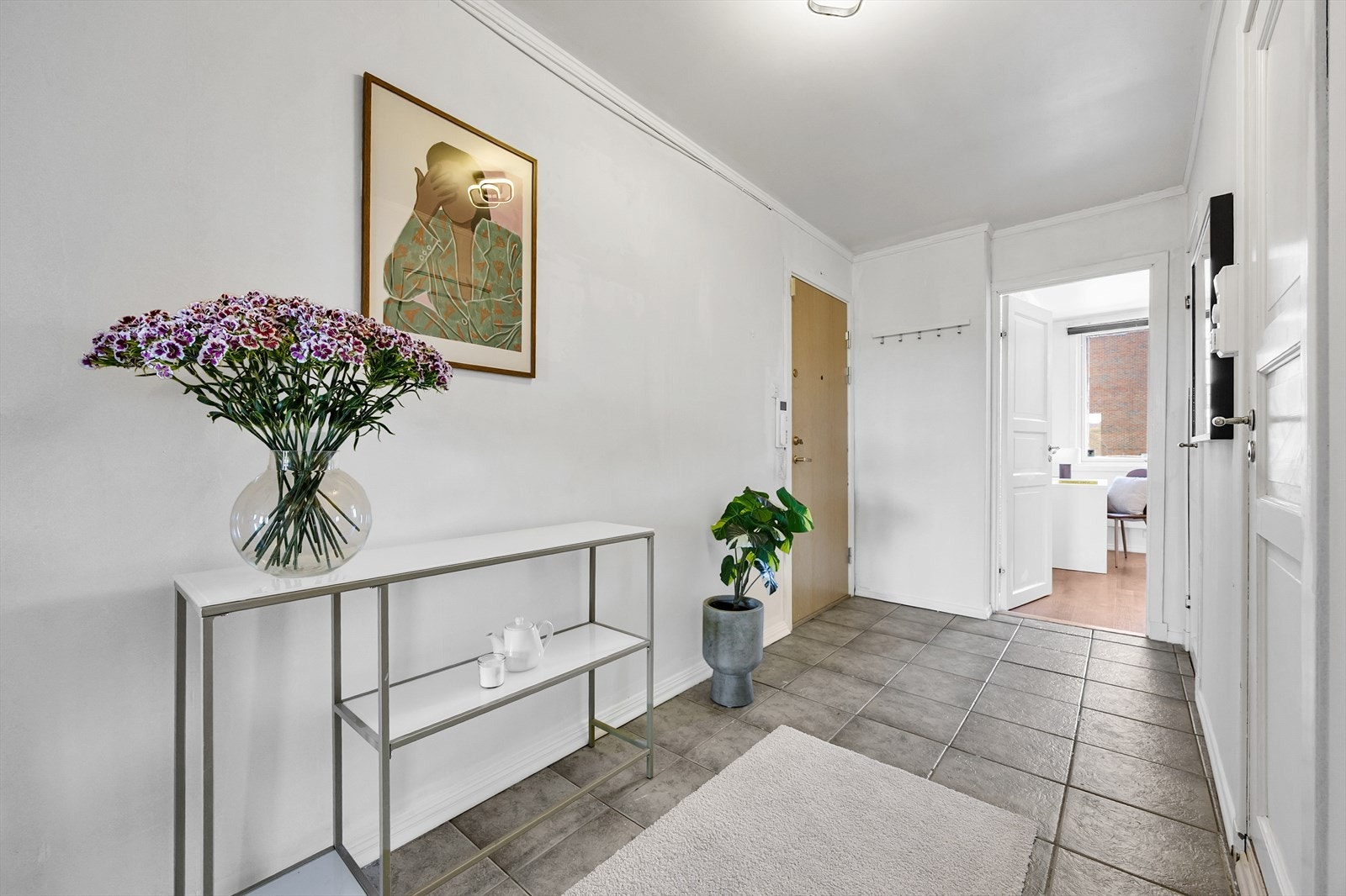 Romslig entré med flislagt gulv og plass til oppheng av yttertøy. Galleribilde