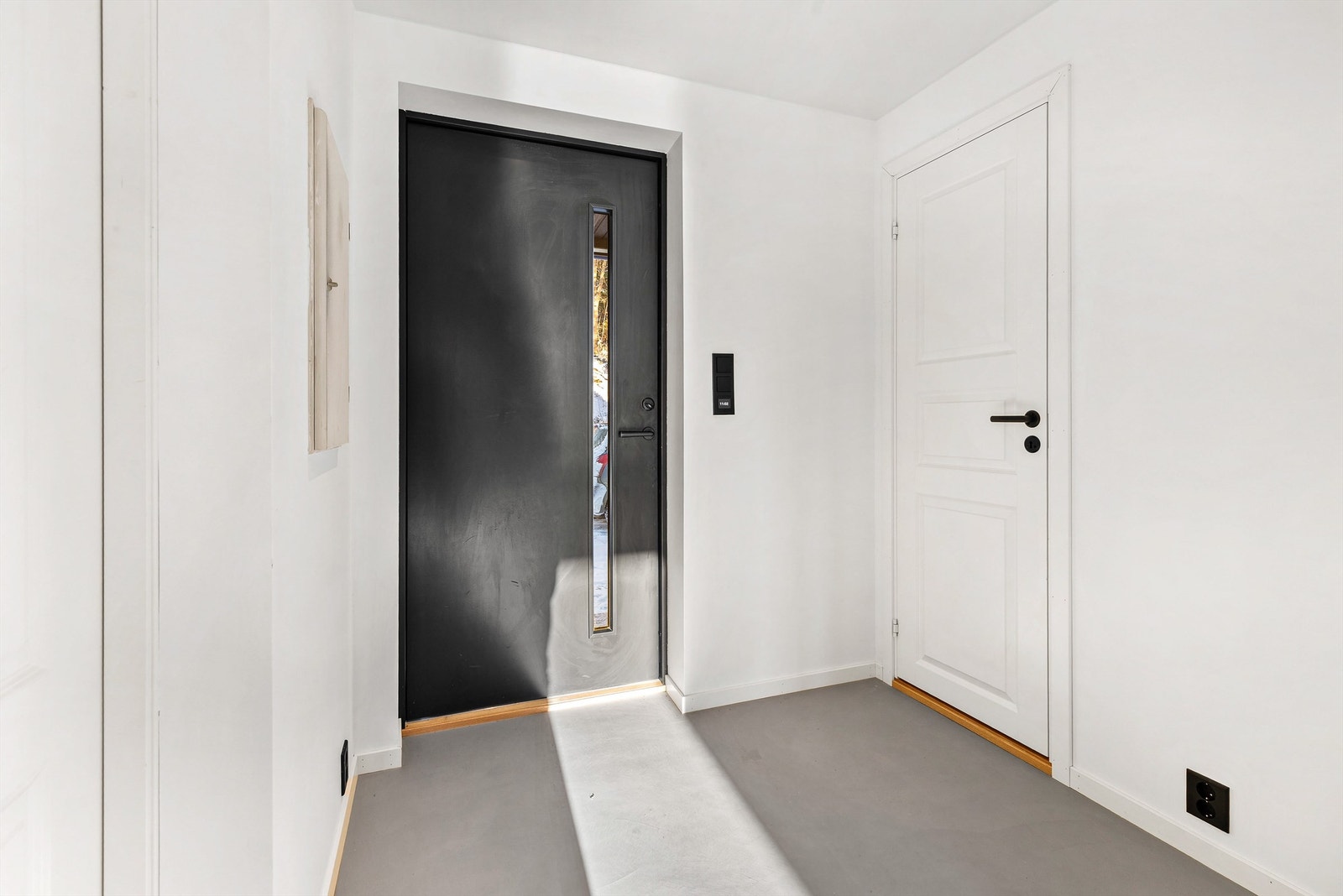 Entré med moderne ytterdør. Gulv med mikrosement og gulvvarme. Galleribilde