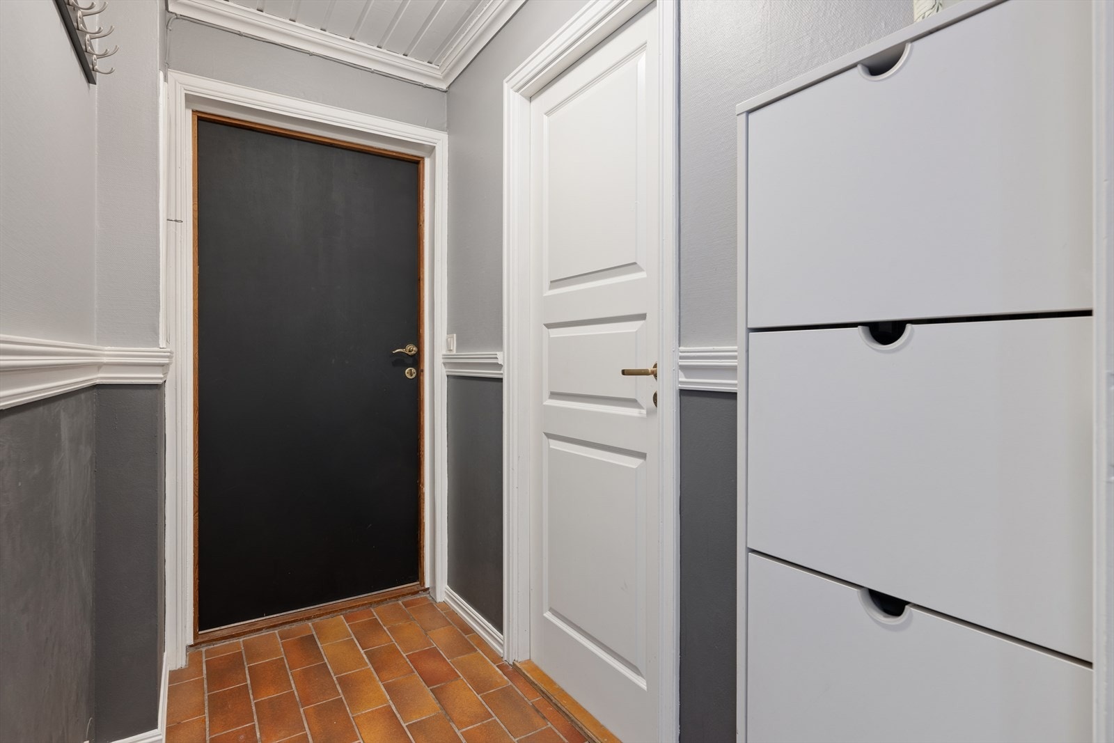 Entréen har flislagt gulv og gråmalte vegger. Fra gangen er det videre adkomst til vaskerom og en hall som har adkomst til de øvrige rommene i underetasjen Galleribilde