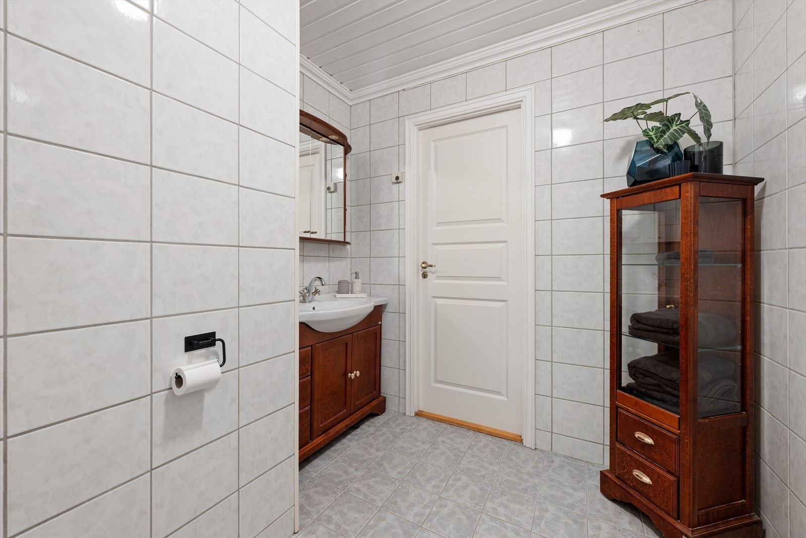 Badet er velholdt og har lyse fliser på gulv og vegger, taket er hvitmalt Galleribilde