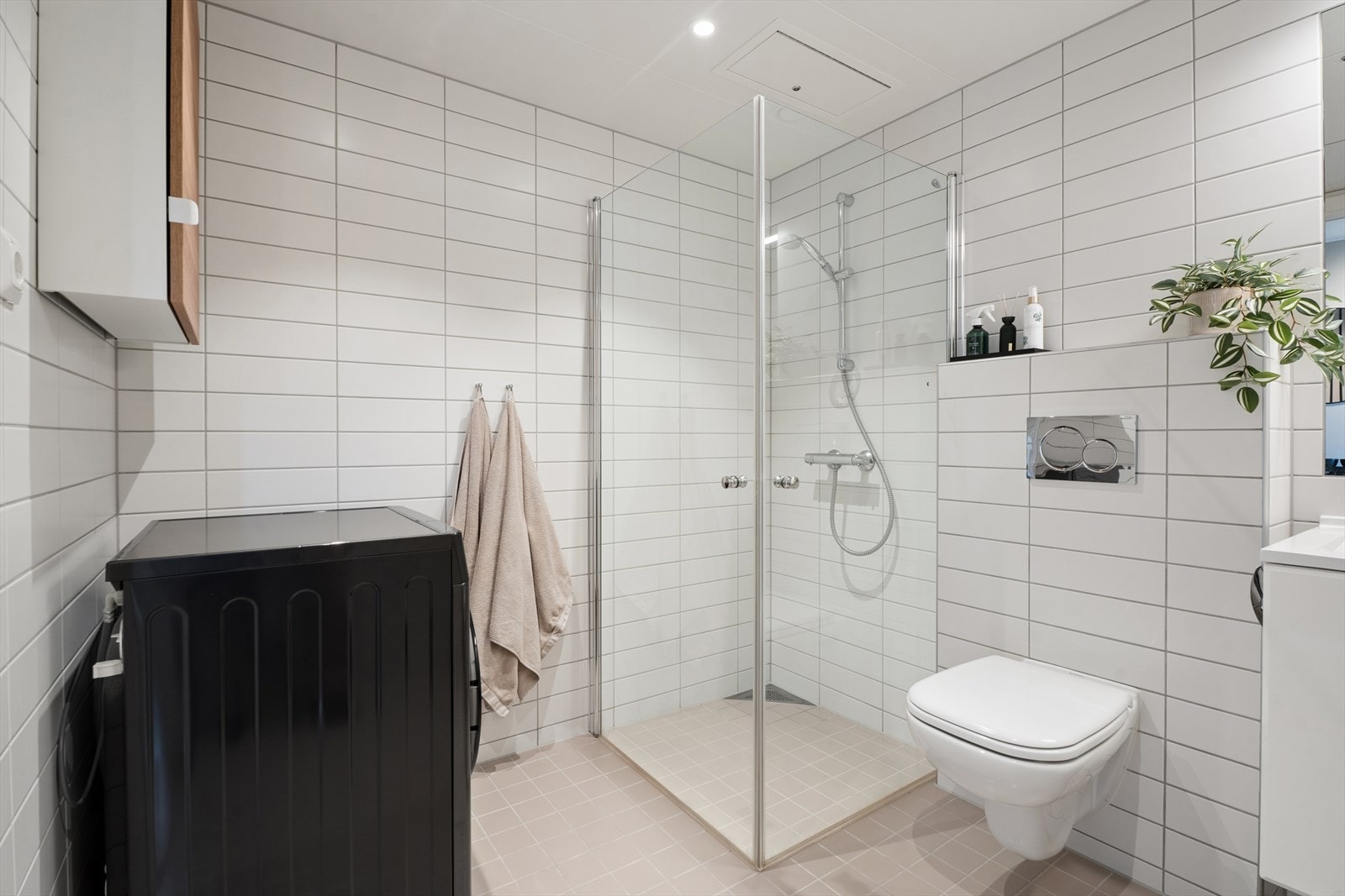 Badet er utstyrt med toalett, dusjhjørne med innfellbare dører i herdet glass, innredning med heldekkende servant og speil, samt opplegg for vaskemaskin. Galleribilde