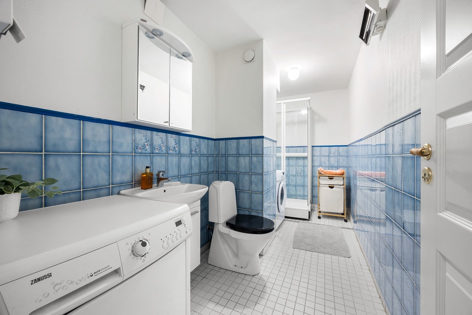 Badet er utstyrt med dusjkabinett, servant med underskap og opplegg for vaskemaskin. Galleribilde