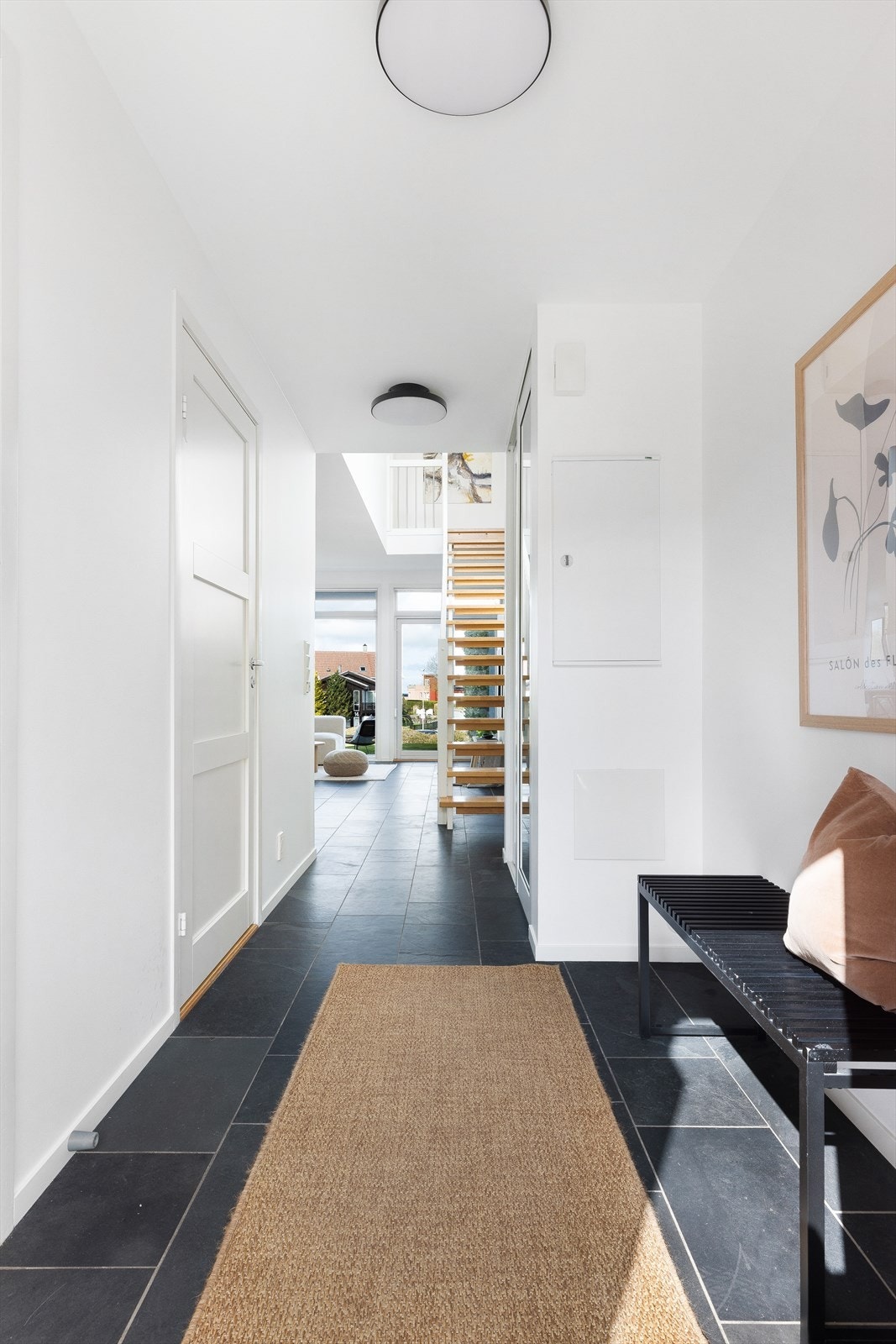 Entréen har skiferfliser på gulv, innebygget skyvedørsgarderobe og leder videre inn til boligens oppholdsrom. Galleribilde
