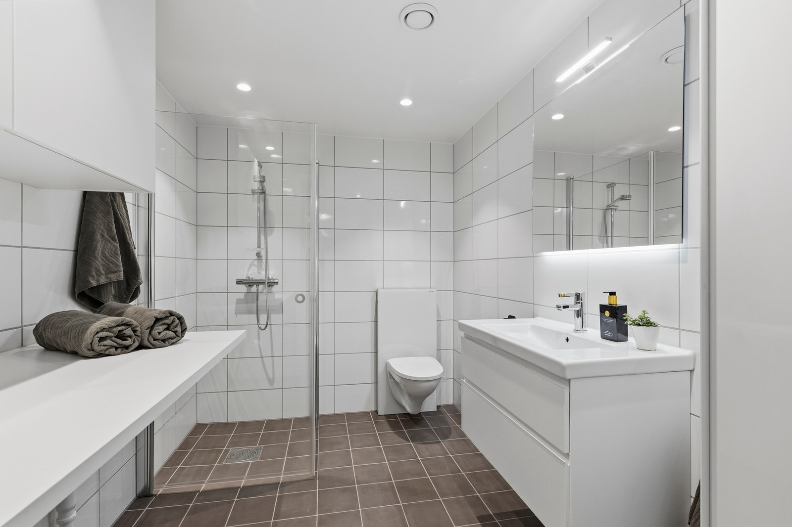 Badet har flislagte overflater på gulv og vegger, gulvvarme og moderne baderomsinnredning. Badet har opplegg for vaskemaskin og gode oppbevaringsmuligheter i innredningen. Galleribilde