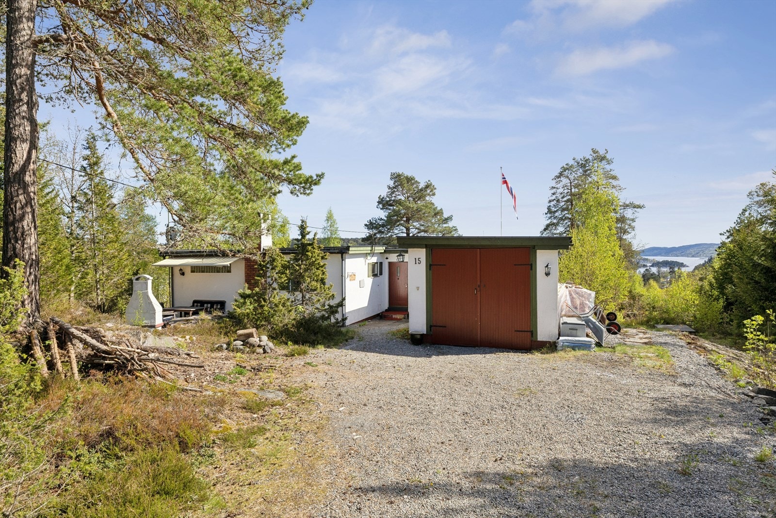 Garasje med sidehengslede porter i tre og grusdekke på gulvet. Rikelig med parkering også på egen tomt. Galleribilde