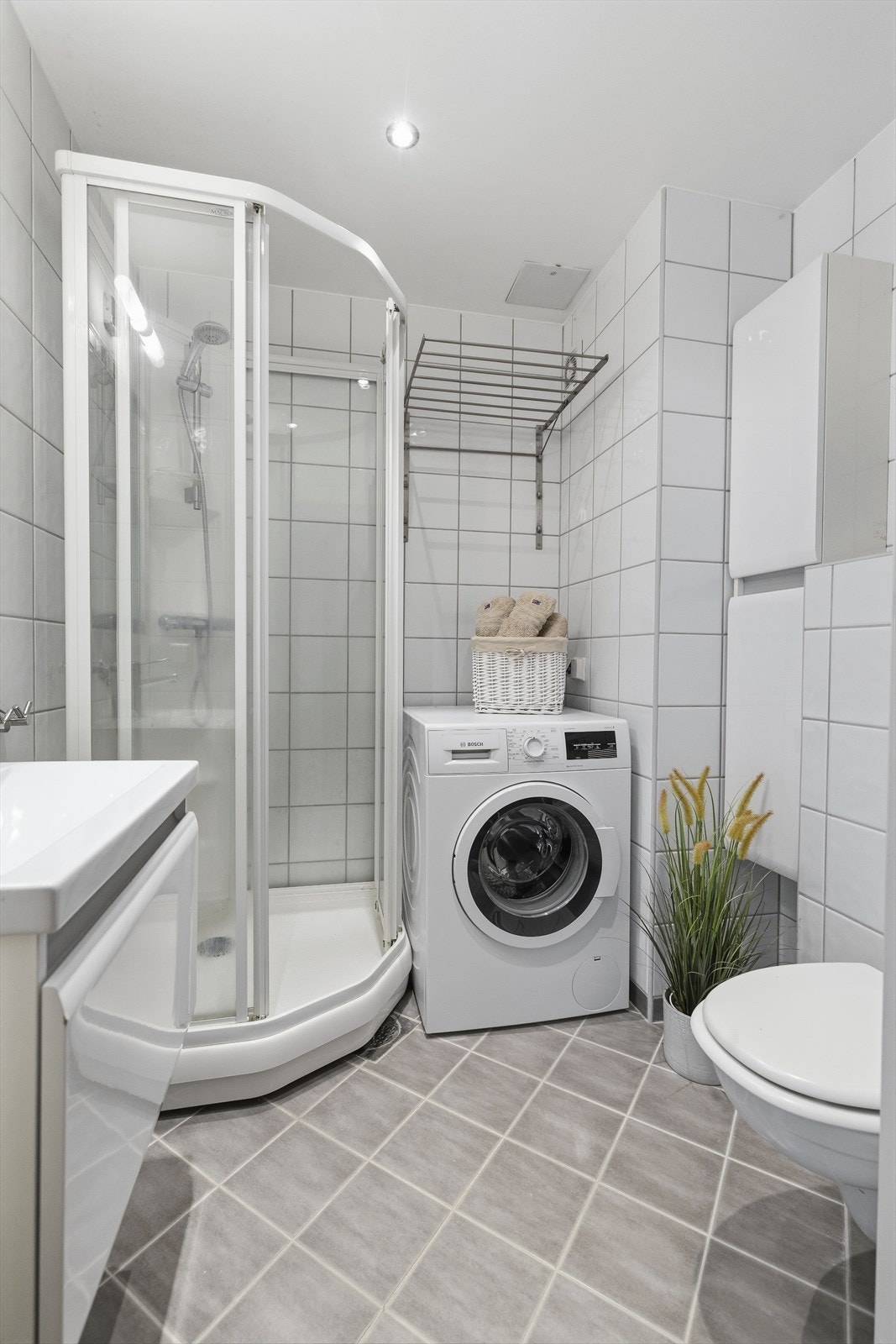 Flislagt bad med varme i gulv og downlights i himling. Baderomskonstruksjoner fra ca. 2009. Servant med skuff under, samt speil med belysning over. Dusjkabinett, veggmontert WC. Vaskemaskin følger med. Galleribilde