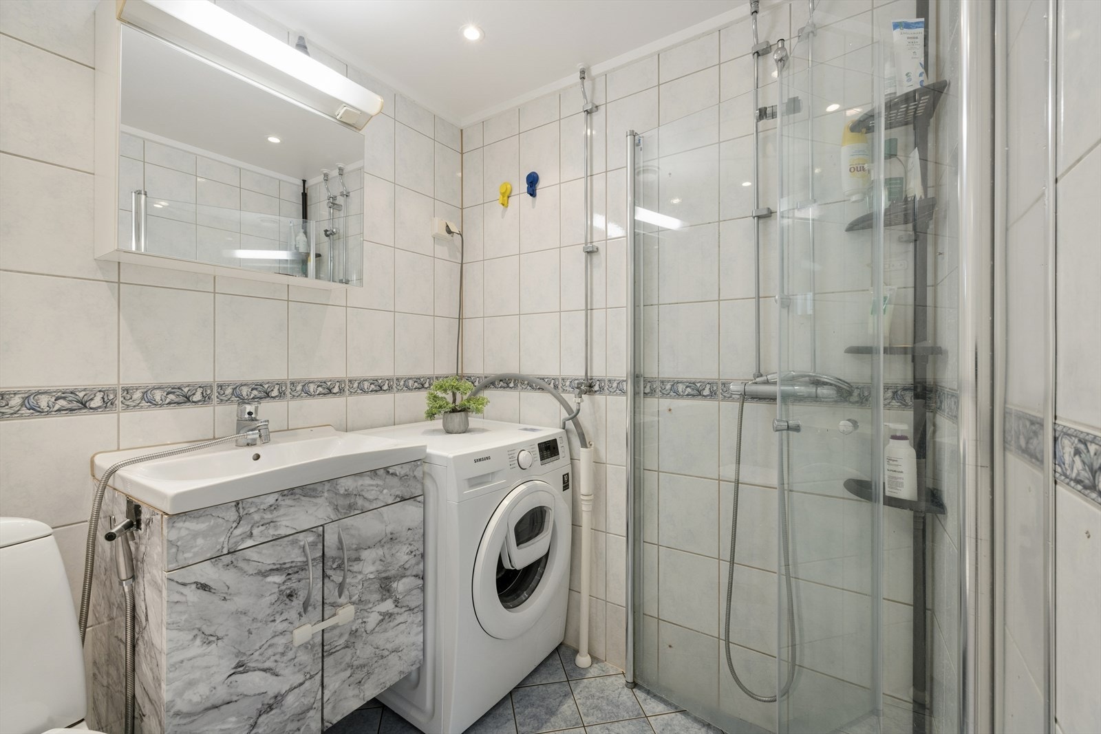 Badet er innredet med nedfelt servant, toalett, dusjhjørne og opplegg for vaskemaskin. Galleribilde