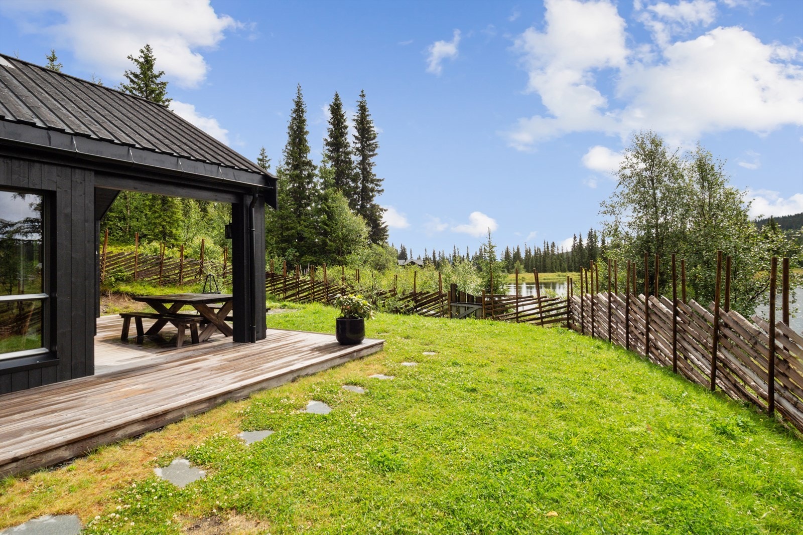 Terrasse og tomt som grenser ned mot tjernet. Galleribilde