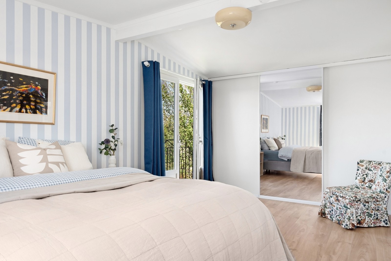 Hovedsoverommet er et lyst rom med tapetserte vegger, skyvedørsgarderobe og utgang til en utkraget balkong med smijernsrekkverk. Galleribilde