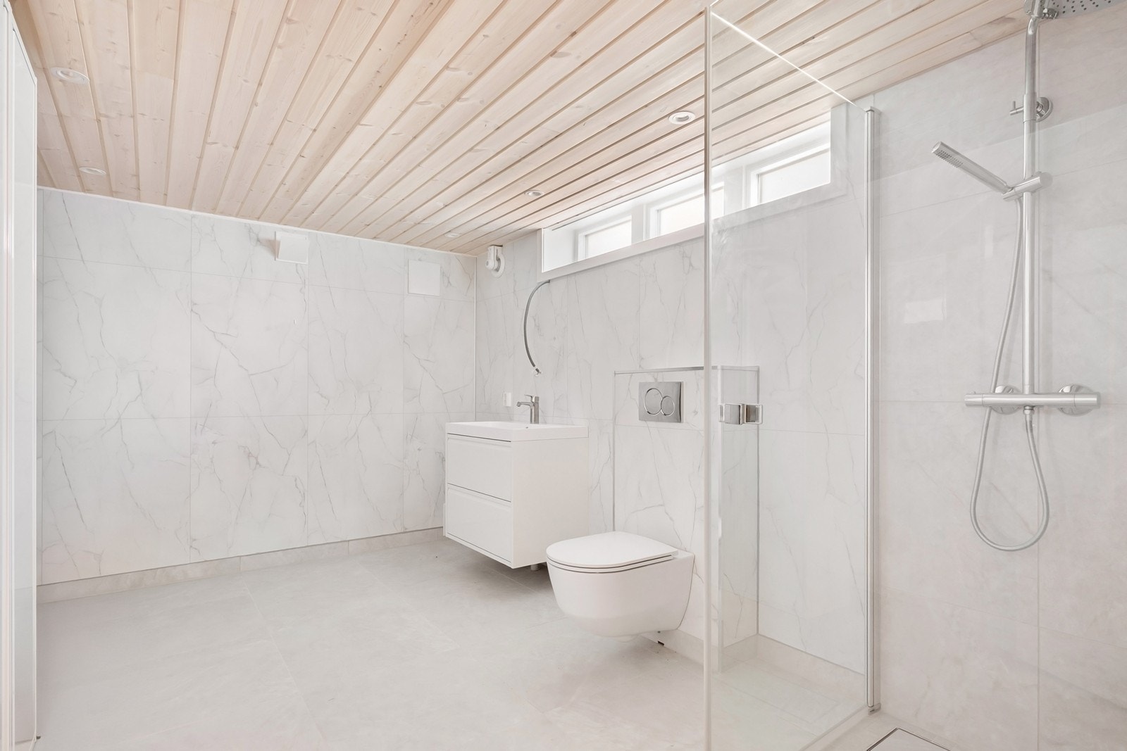 Badet i kjelleren er nytt fra 2026. Rommet har lyse fliser i 60x60-format på gulv med gulvvarme og baderomsplater på vegger. Galleribilde