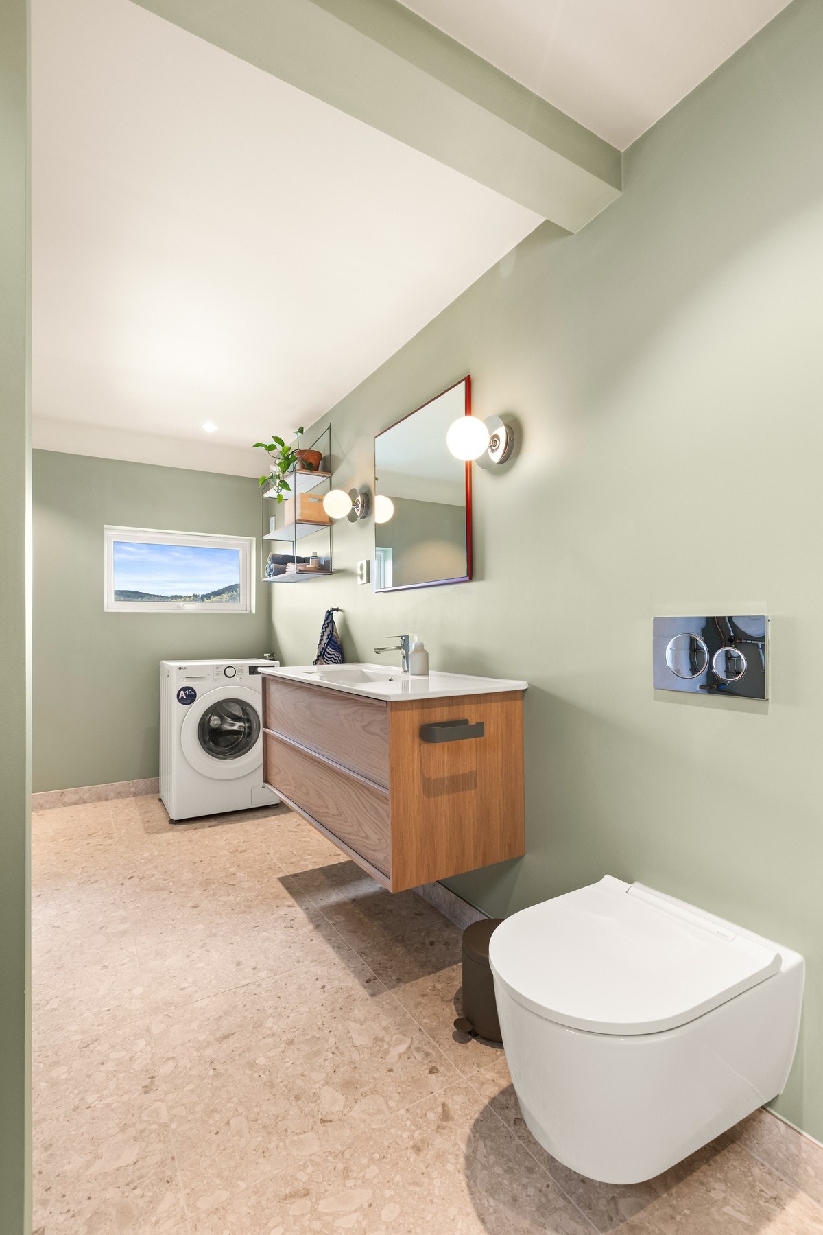 Badet er delvis flislagte overflater, vannbåren gulvvarme, dusjnisje, vegghengt servantinnredning, toalett og opplegg for vaskemaskin. Galleribilde