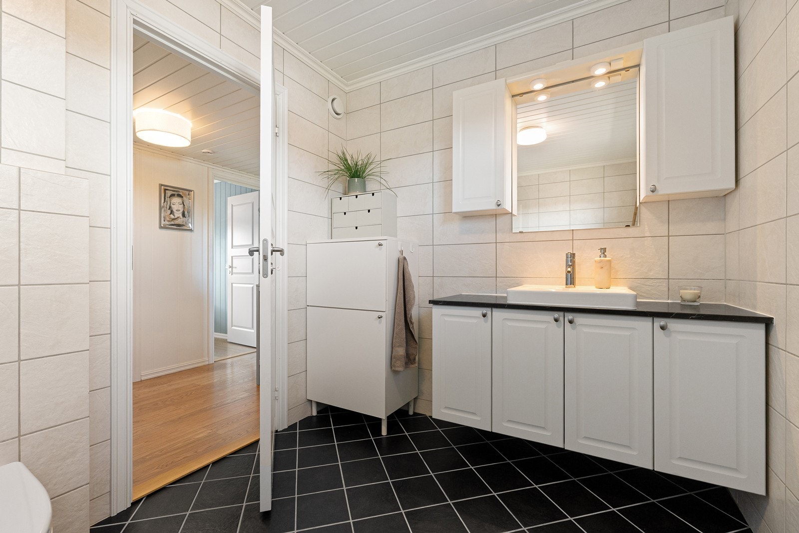 Badet er innredet med servant i baderomsinnredning, vegghengt toalett og badekar med dusjarmatur på vegg. Galleribilde